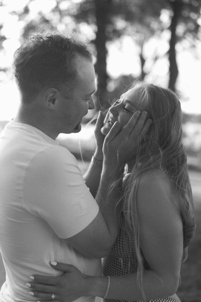 Guy grabbing his girl's face before kissing her for their engagement photographer in Excelsior