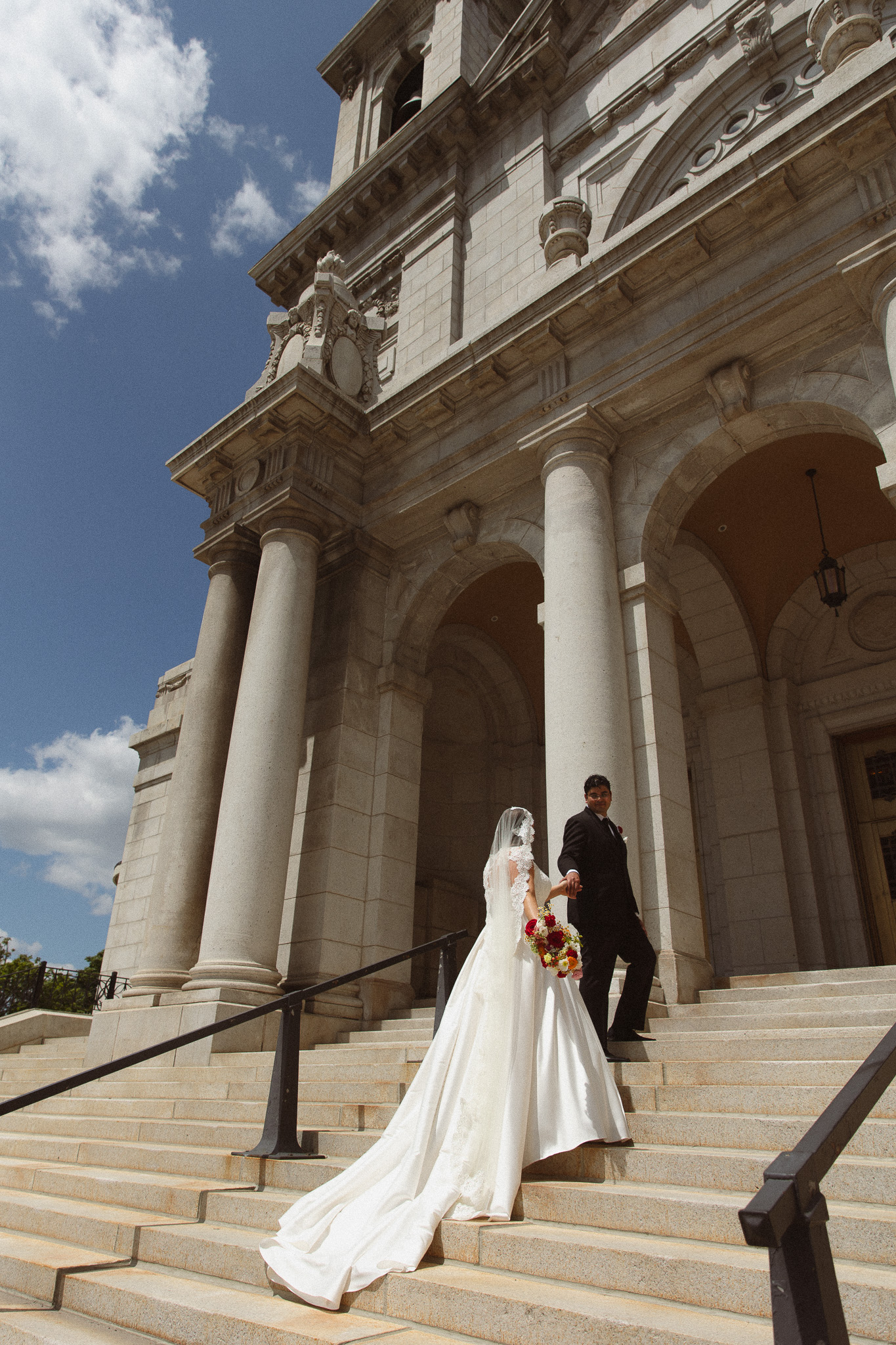 Bride and groom walking up the stairs of the Basilica of St. Mary church in Minneapolis before their ceremony