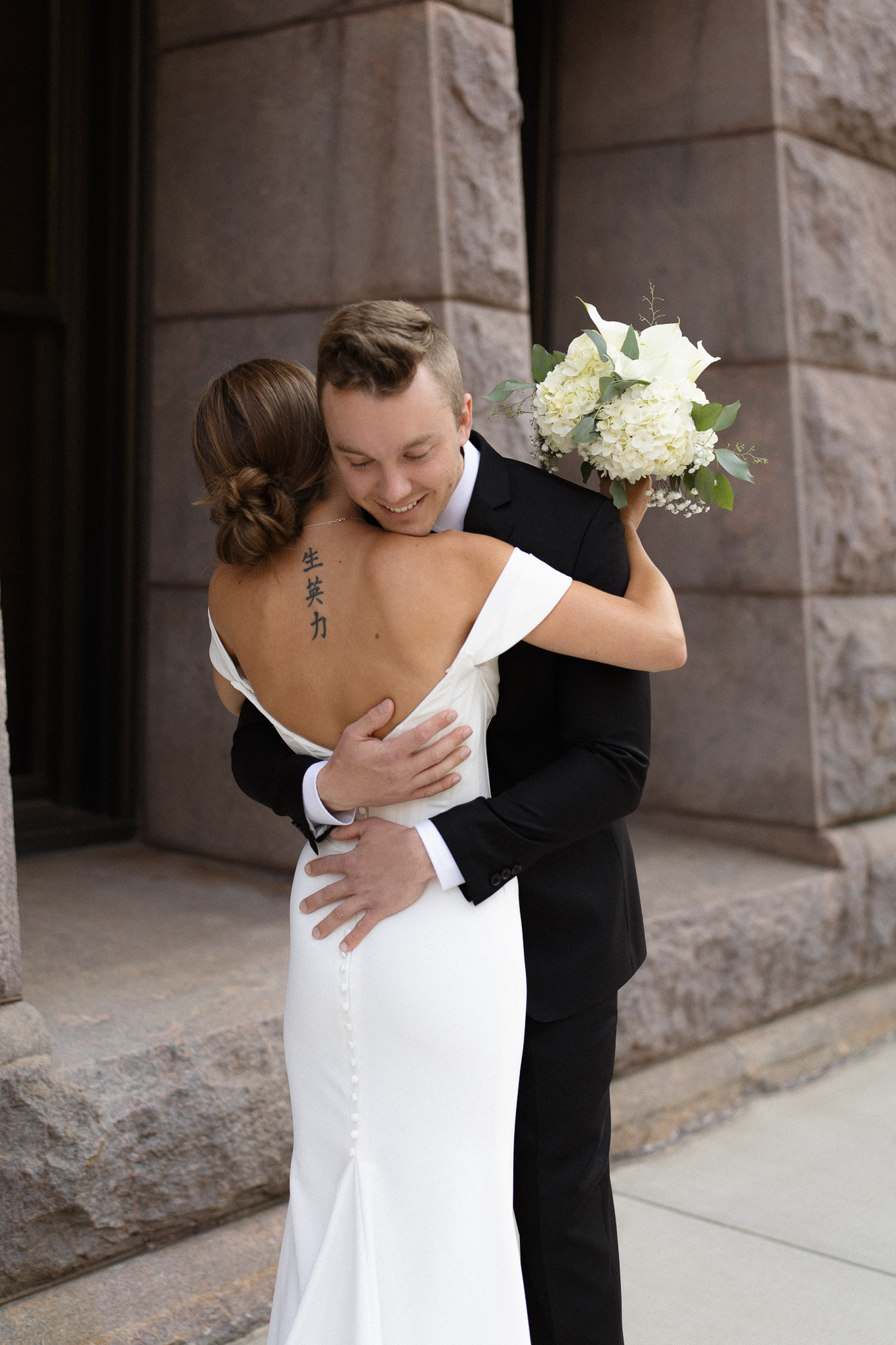 Groom hugging his bride during their first look outside the Minneapolis City Hall building