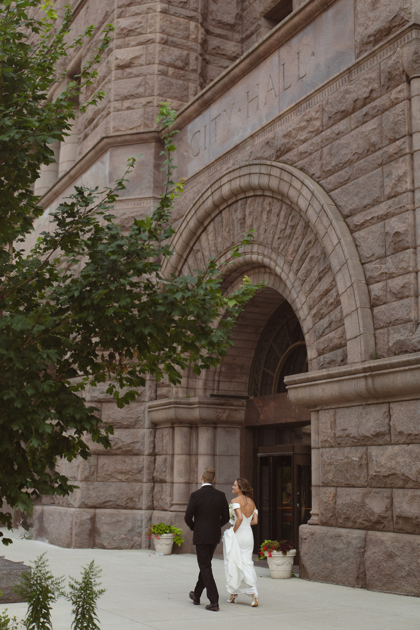 Bride and Groom walking across the street with the Minneapolis City Hall in the background