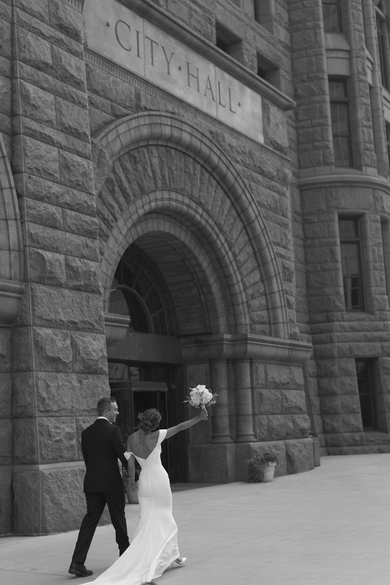 Bride and Groom walking past the Minneapolis City Hall building during their elopement portraits