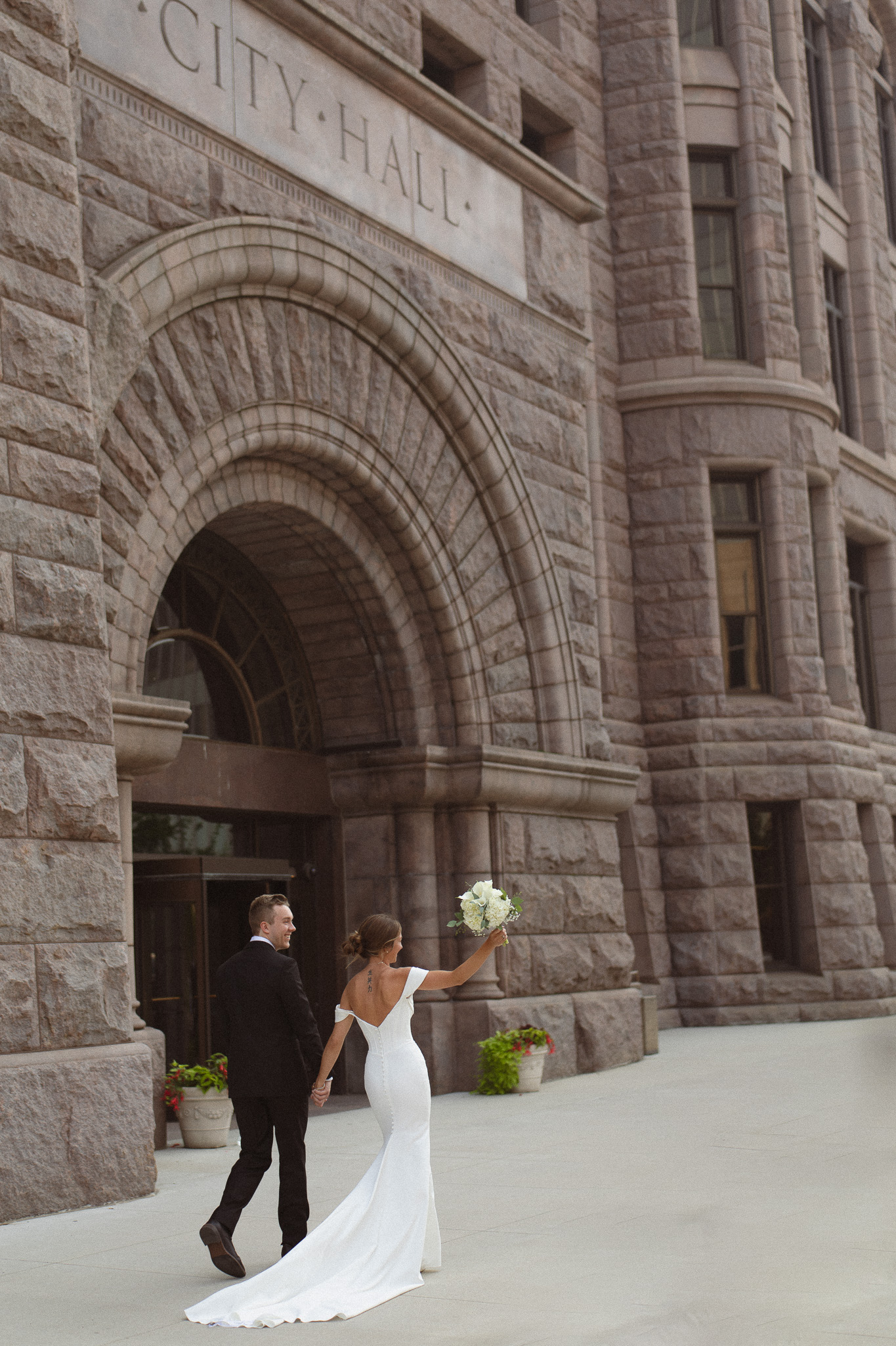 Bride and Groom walking past the Minneapolis City Hall building after eloping