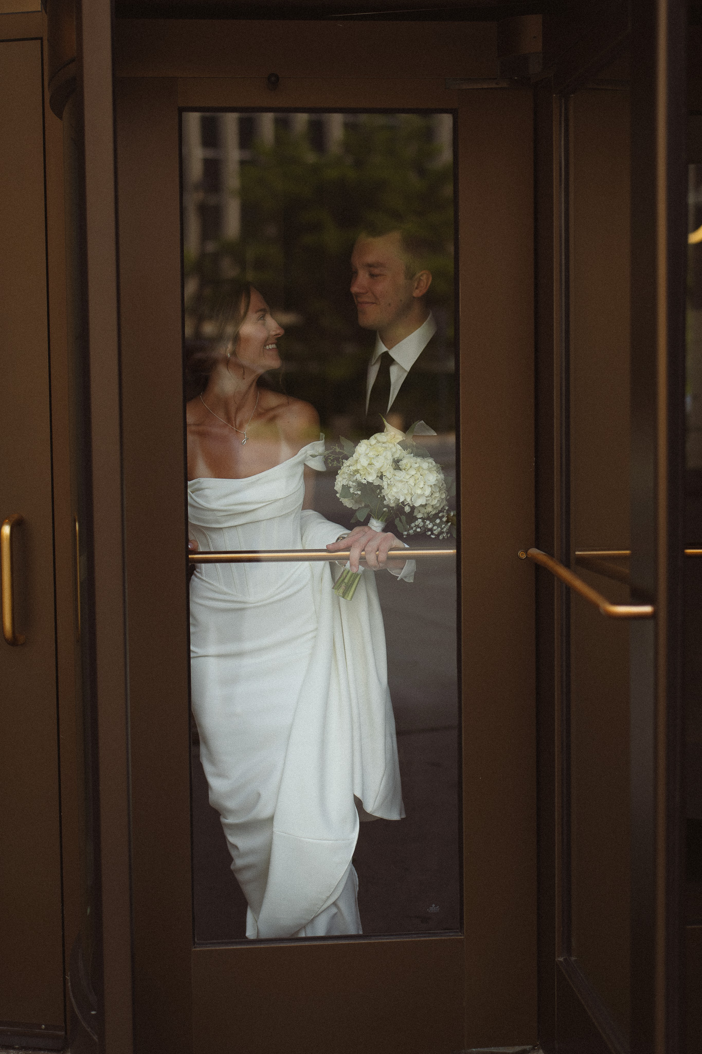 Bride and Groom walking through the spinning door together after eloping at the City Hall in Minneapolis