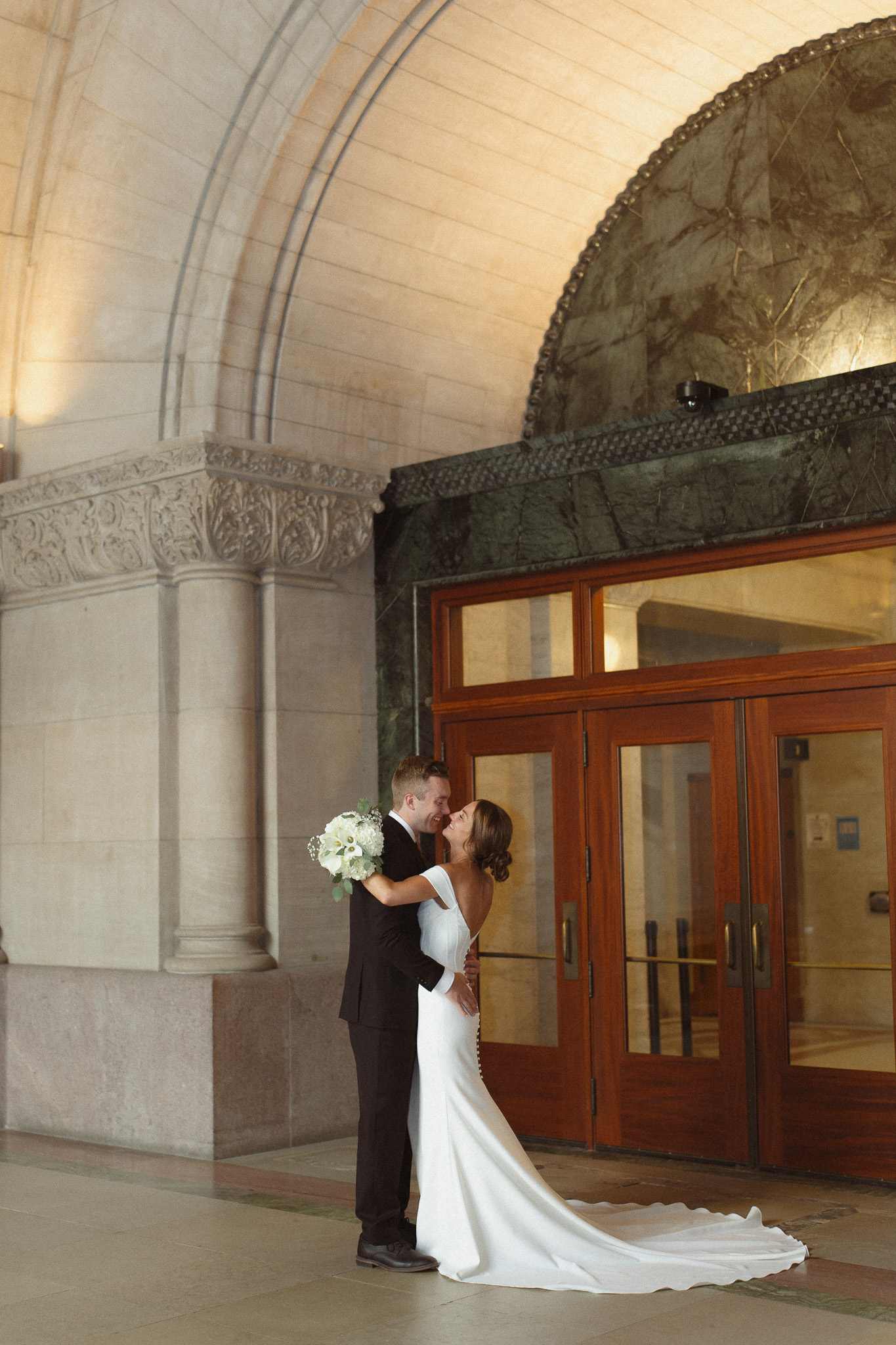 Bride and Groom wide shot underneath the arch at the Minneapolis City Hall 
