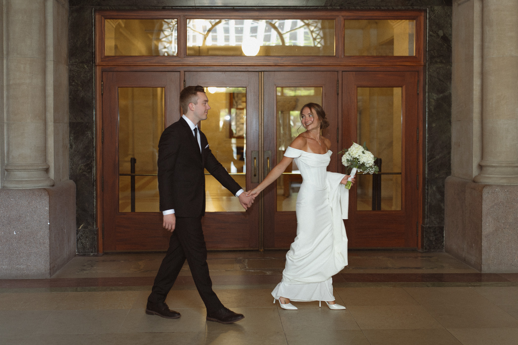 Bride leading Groom down the hallway in the Minneapolis City Hall