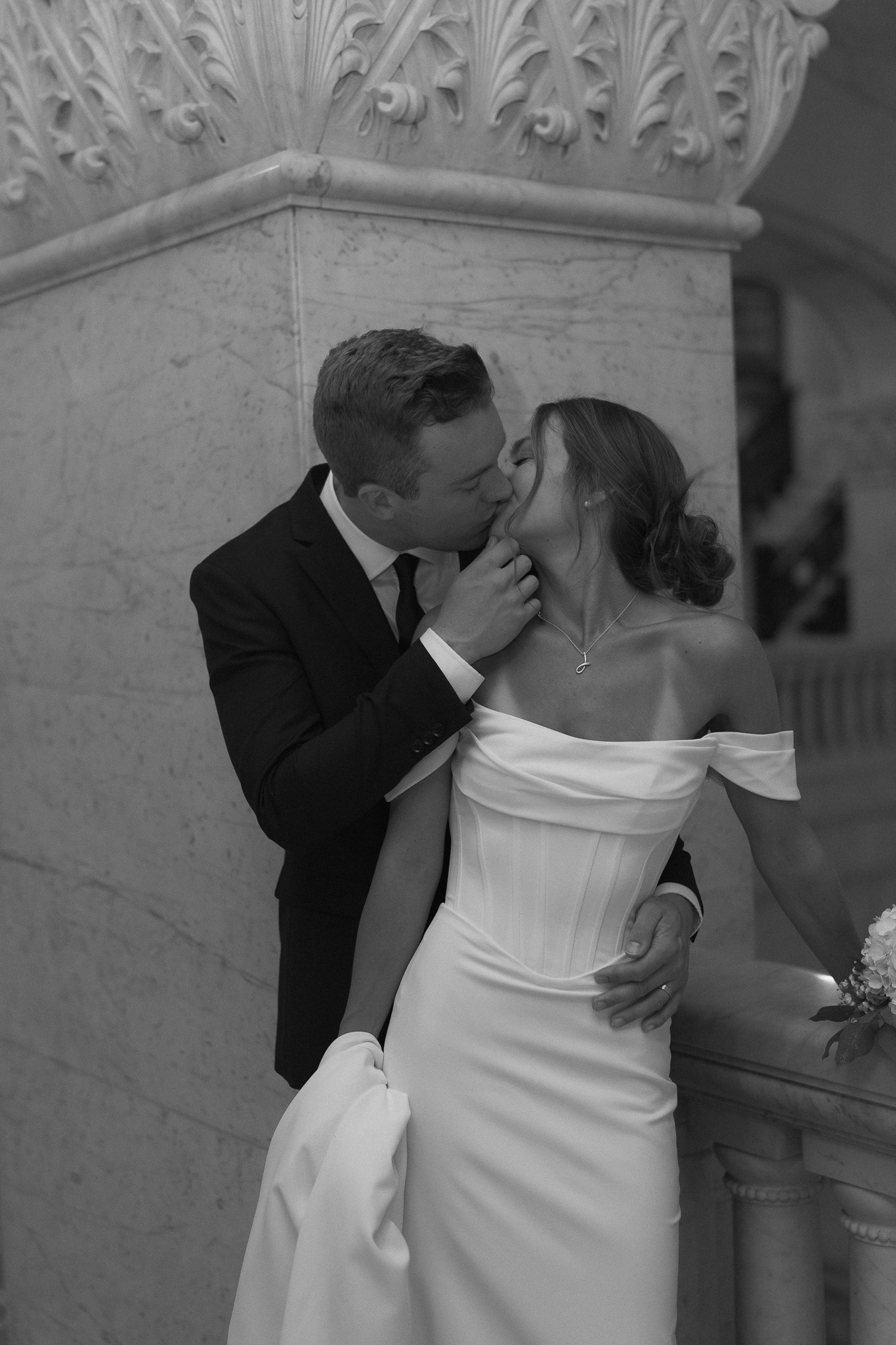 Bride and Groom black and white cinematic portrait of groom grabbing bride's chin for a kiss