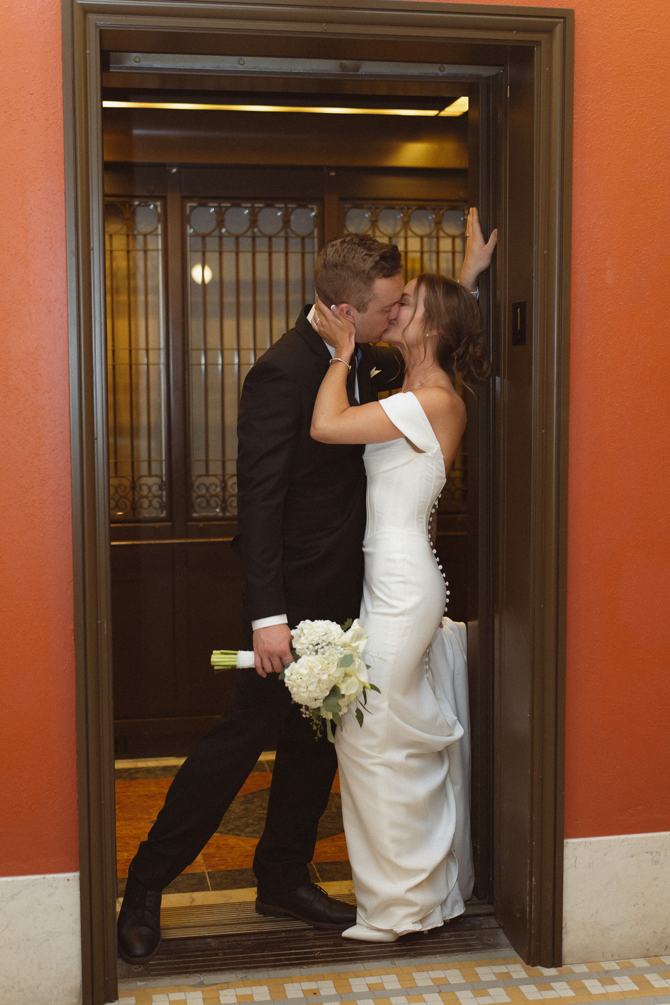 Groom kissing his bride passionately inside the elevator as the doors are closing