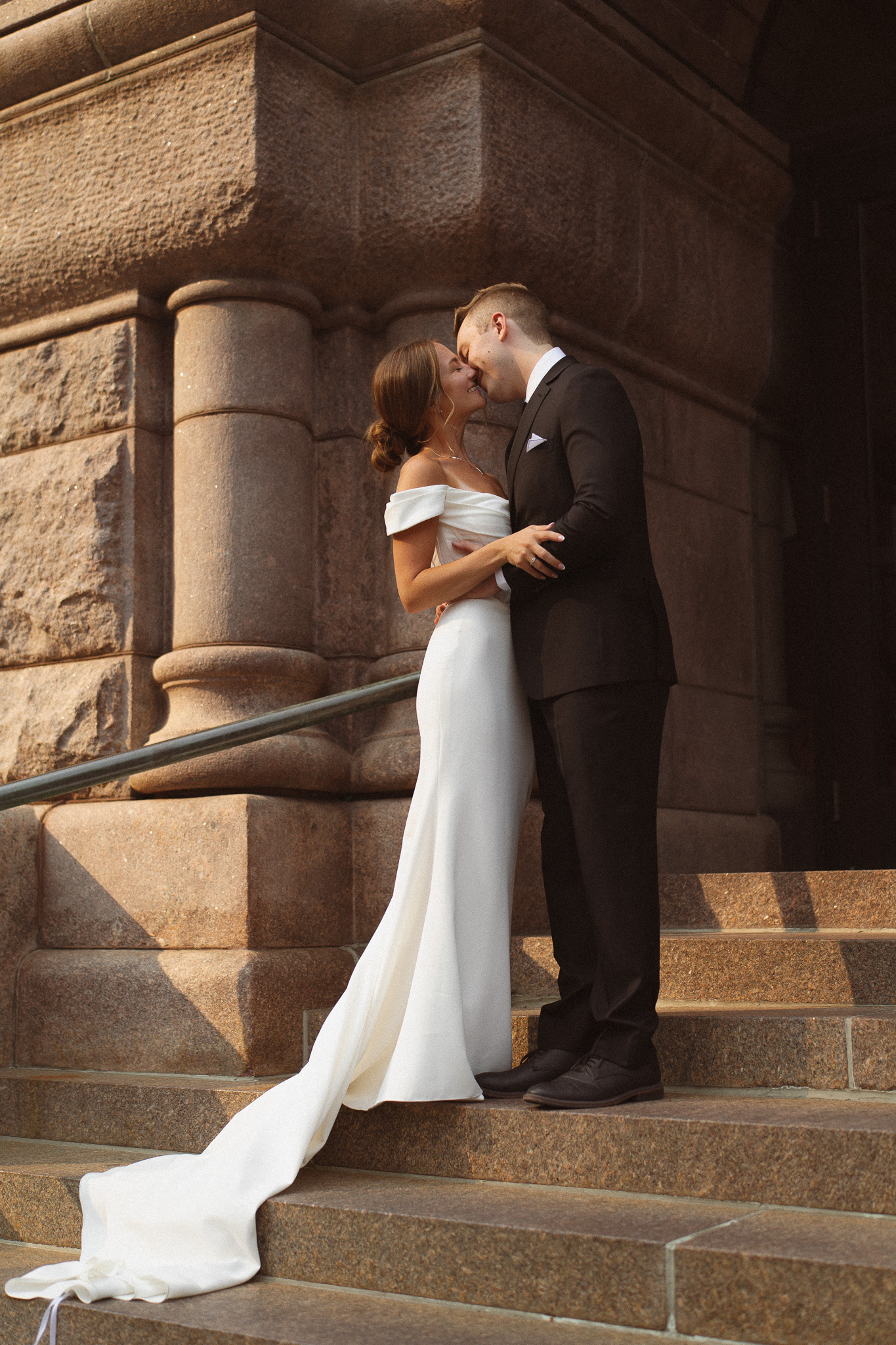 Groom kissing his bride on the stairs outside the City Hall building in Minneapolis