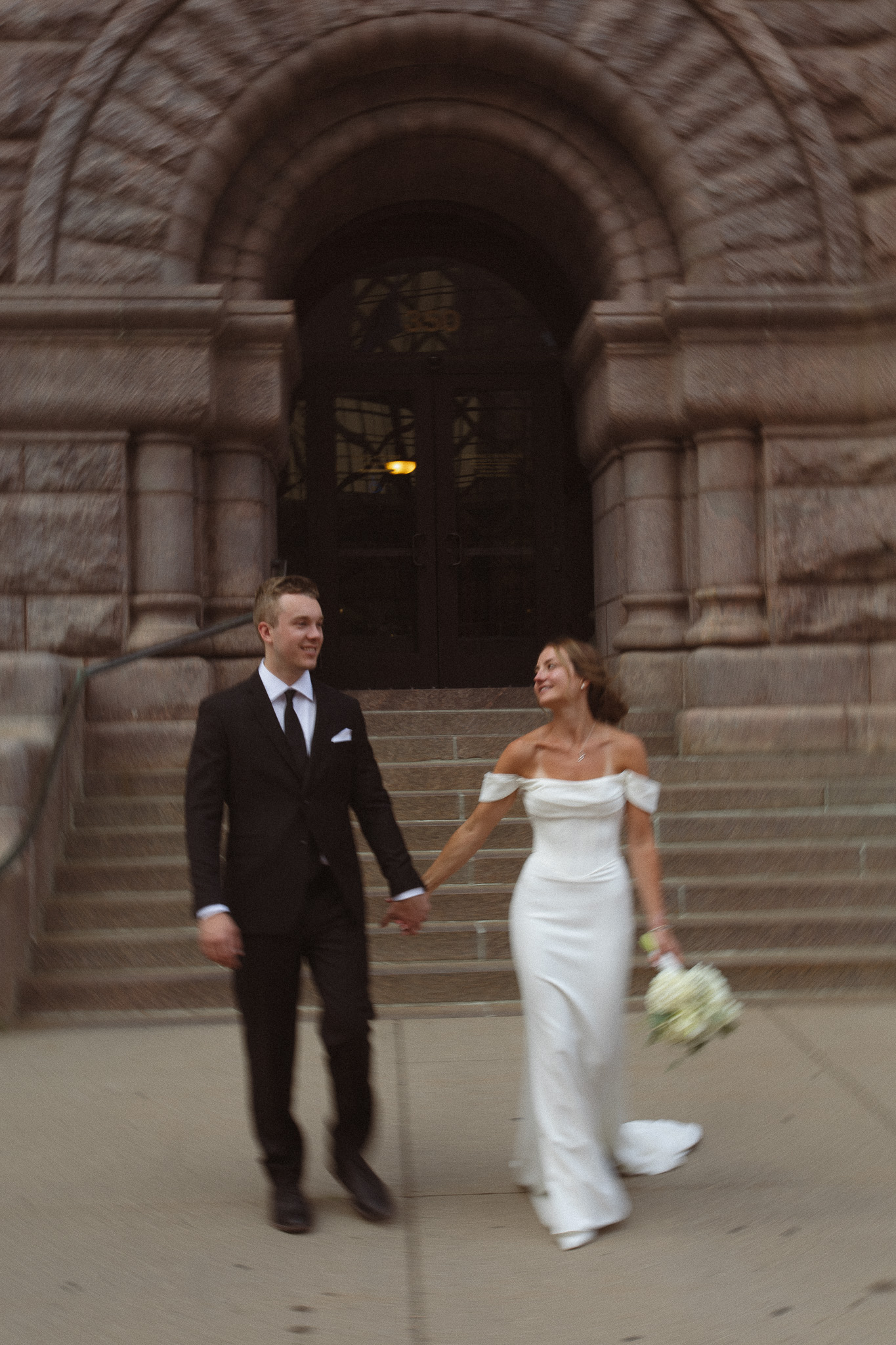 Documentary, cinematic photo of bride and groom walking outside the city hall in Minneapolis
