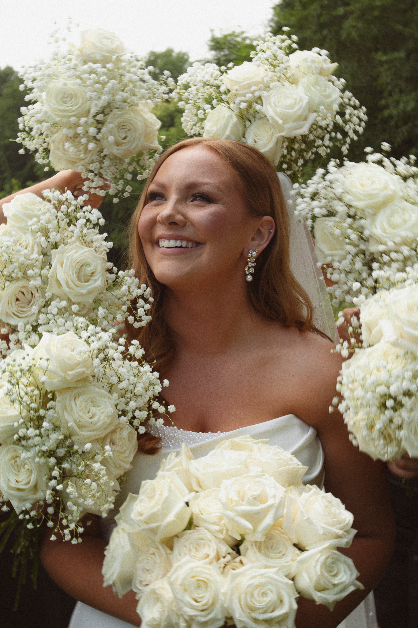 Bride surrounded by all her bridesmaids bouquets while she smiles into the air