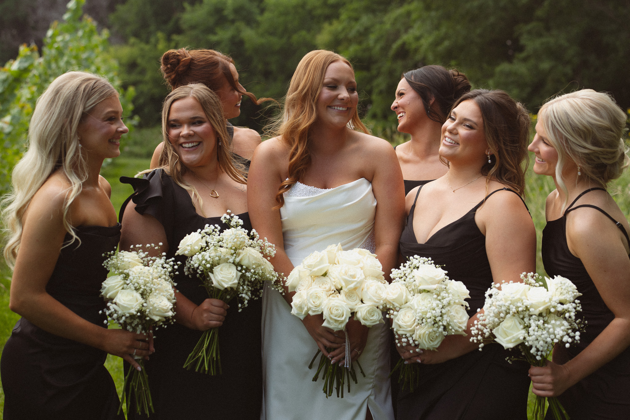 Bridal party group shot of bridesmaids holding their bouquets and smiling at each other in Wayzata