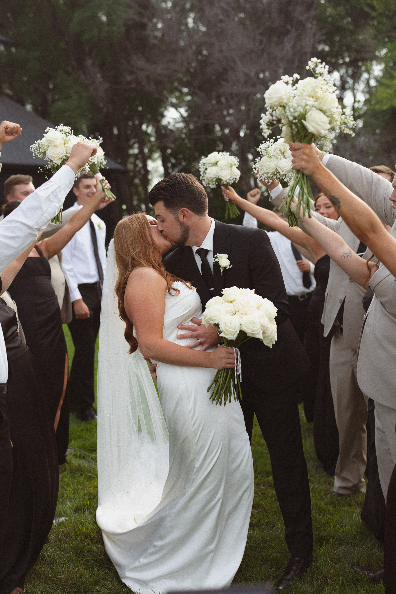 The wedding party creating a receiving line cheering on the wedding couple as they run through and kiss
