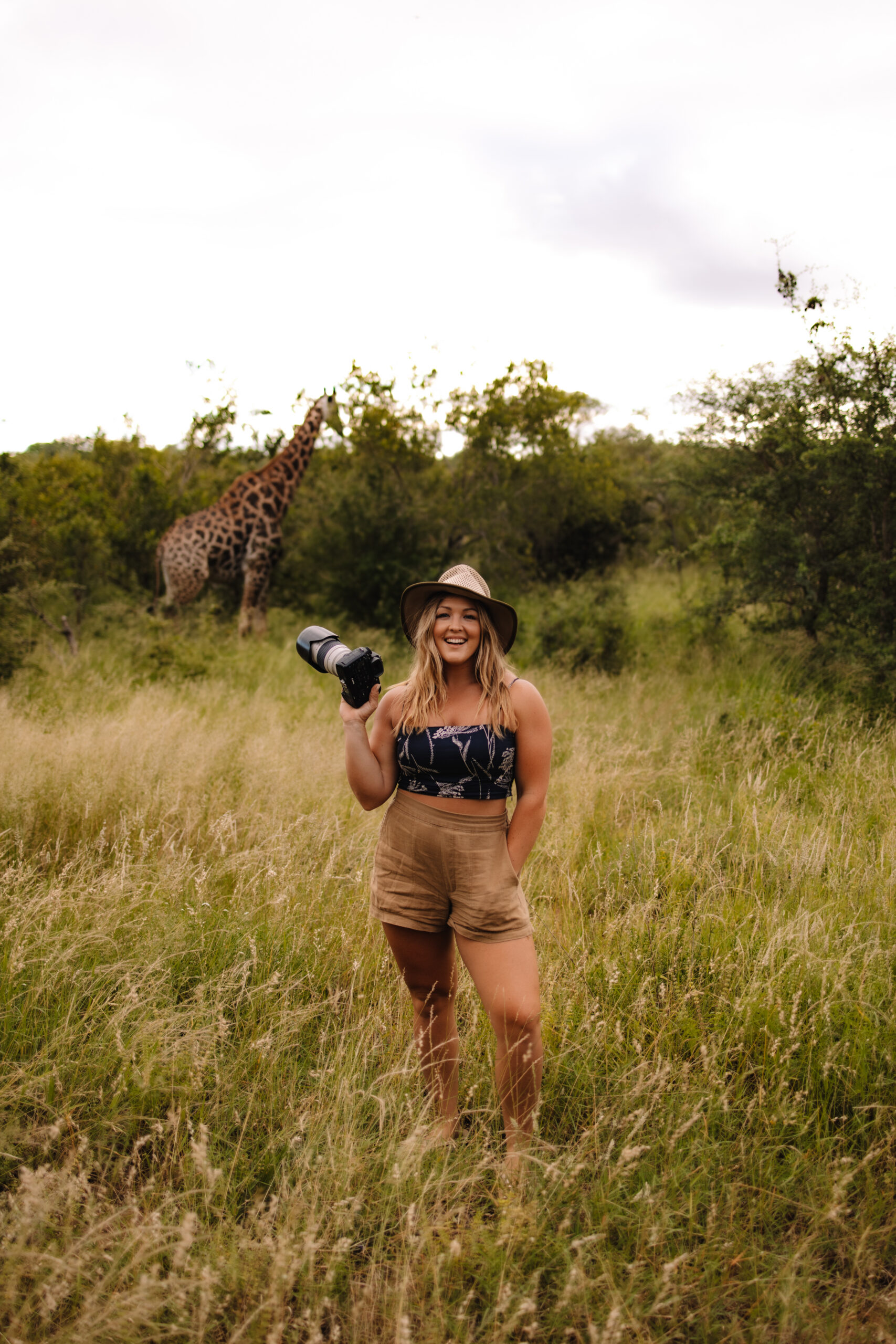 Heidi Straus photographing at a private South African game reserve with a giraffe nearby