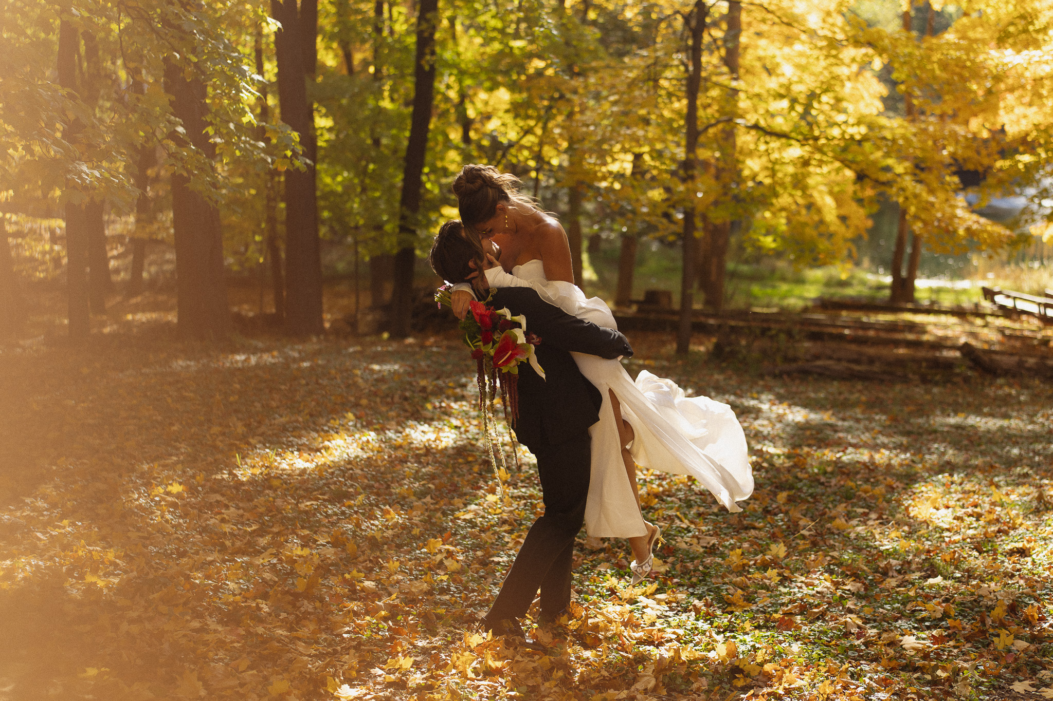 Groom picking up and spinning his bride surrounded by the Fall colors at The Woods Retreat Orono MN wedding