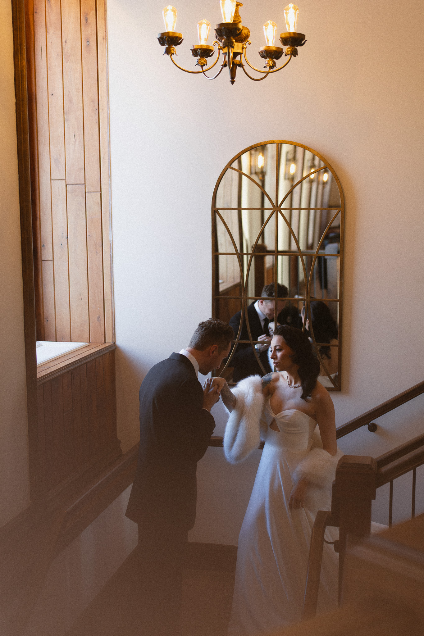 Groom leading his bride down the beautiful staircase at the Woods Retreat Wedding Venue in Orono, MN