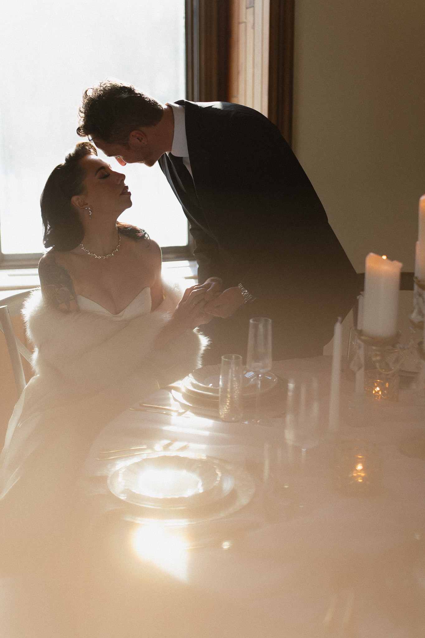Groom leaning in to kiss his bride at the reception table at their The Hutton House wedding