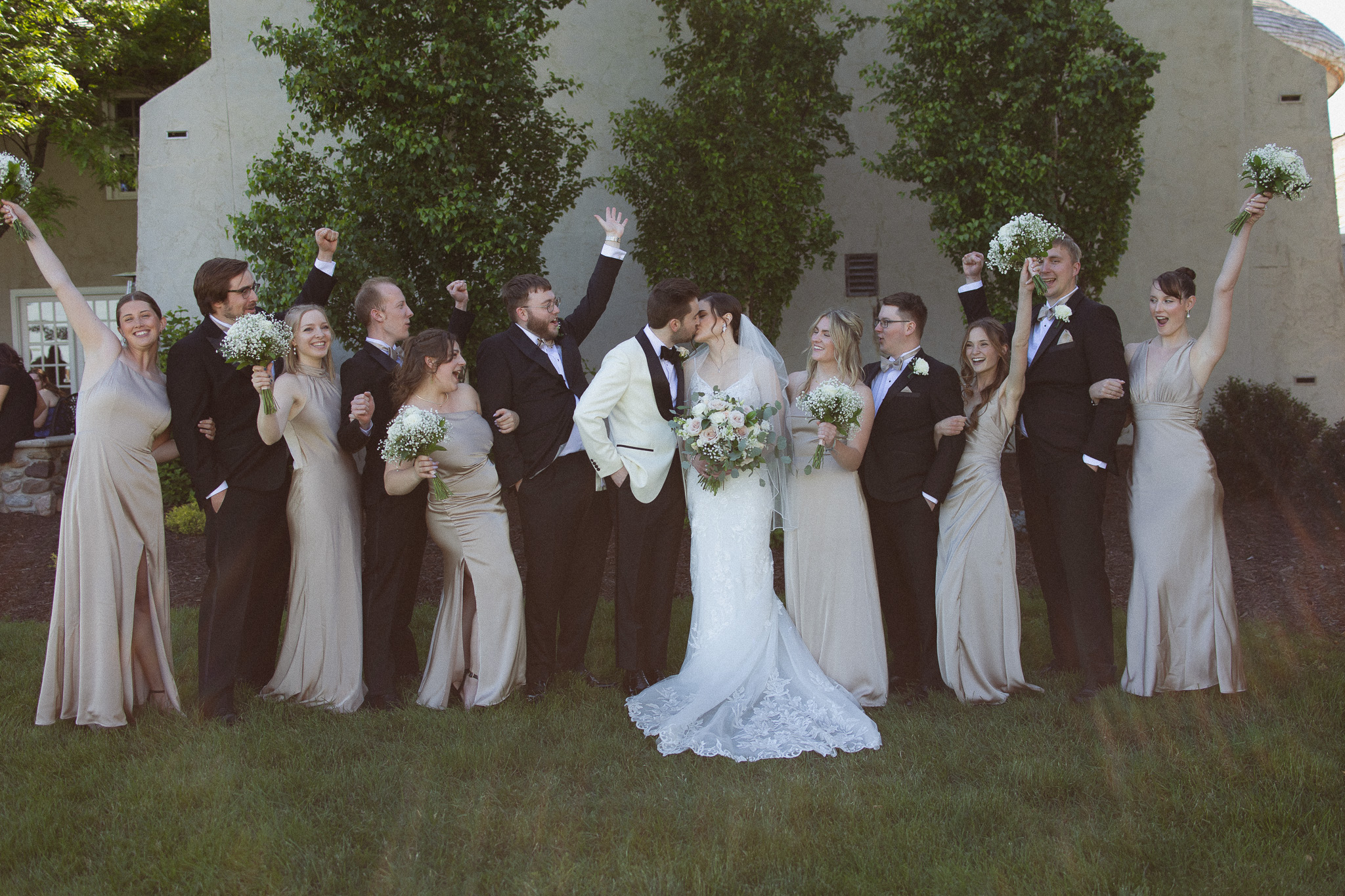 Bridal party standing together next to the bride and groom cheering at Bavaria Downs during an elegant West Metro wedding