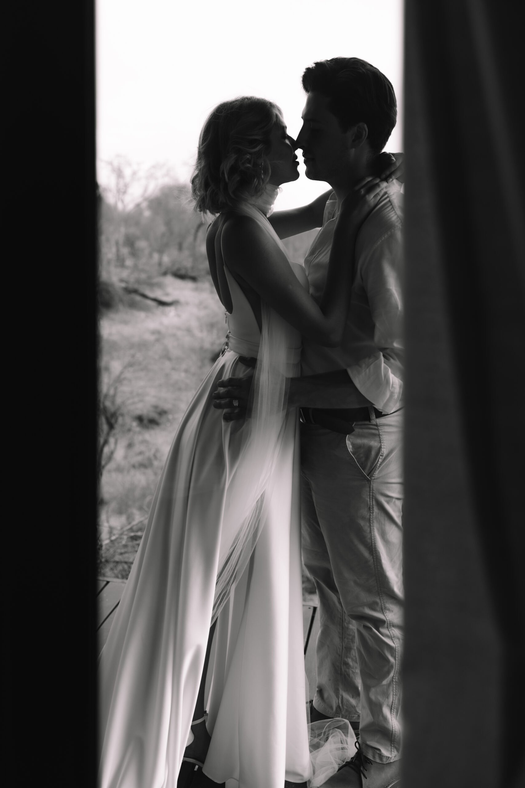 Black and white image of bride and groom sharing a quiet embrace in the African bush