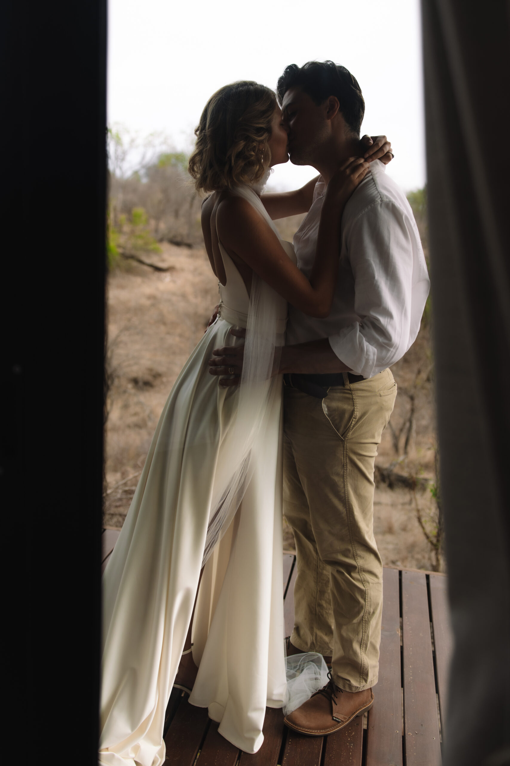Bride and groom embracing in the doorway of a safari tent lodge at golden hour