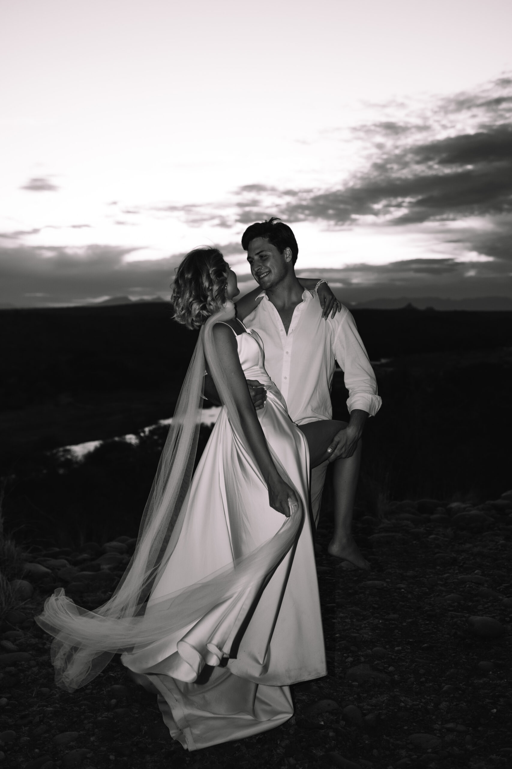 Black and white portrait of a bride and groom dancing together on a scenic African overlook