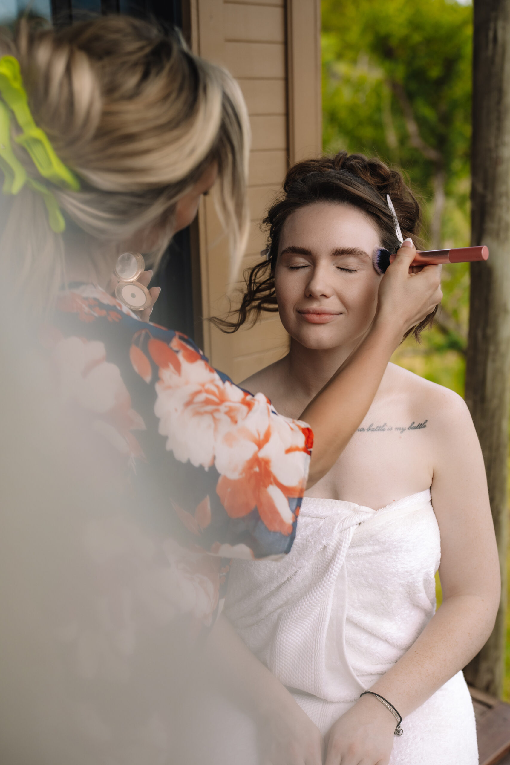 Bride having makeup applied outdoors while getting ready at a safari lodge