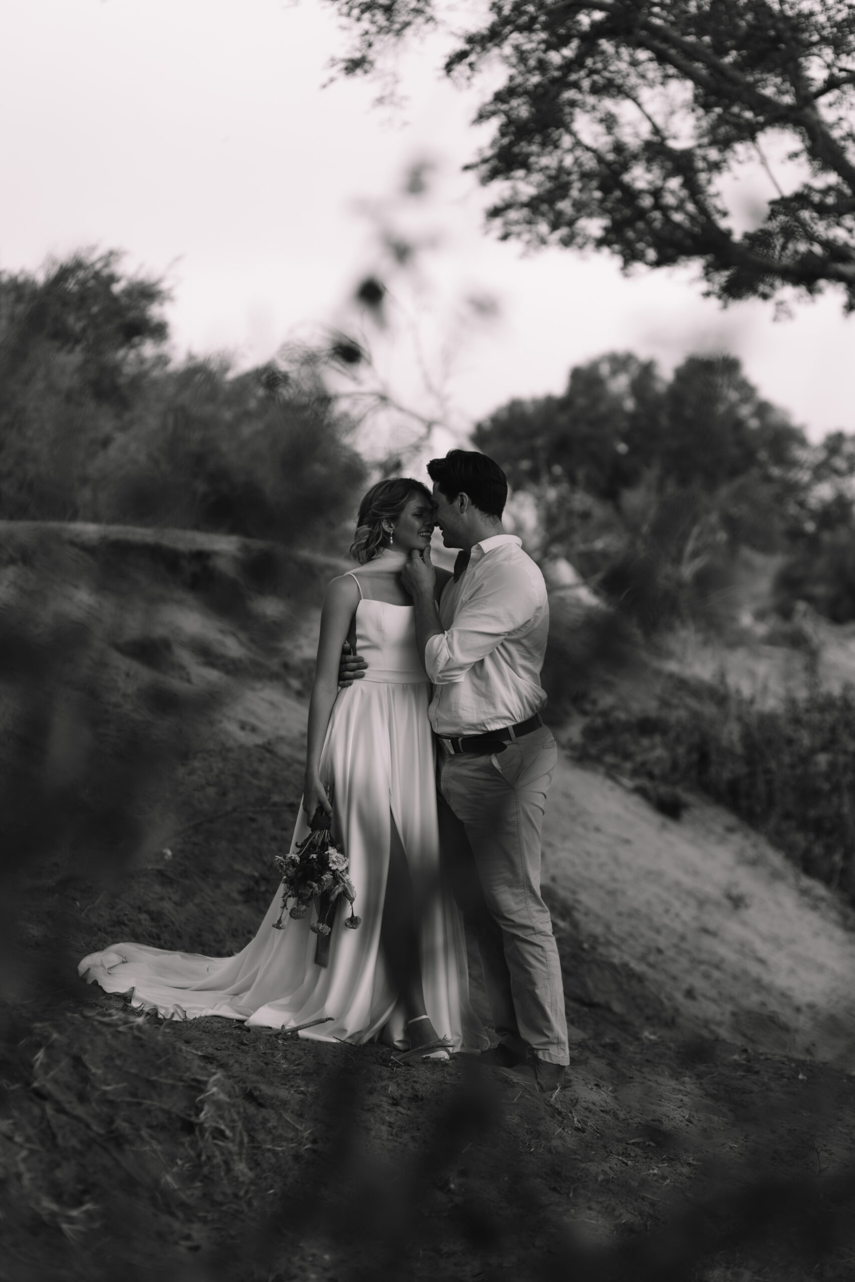 Black and white portrait of bride and groom embracing in the doorway of a safari tent lodge
