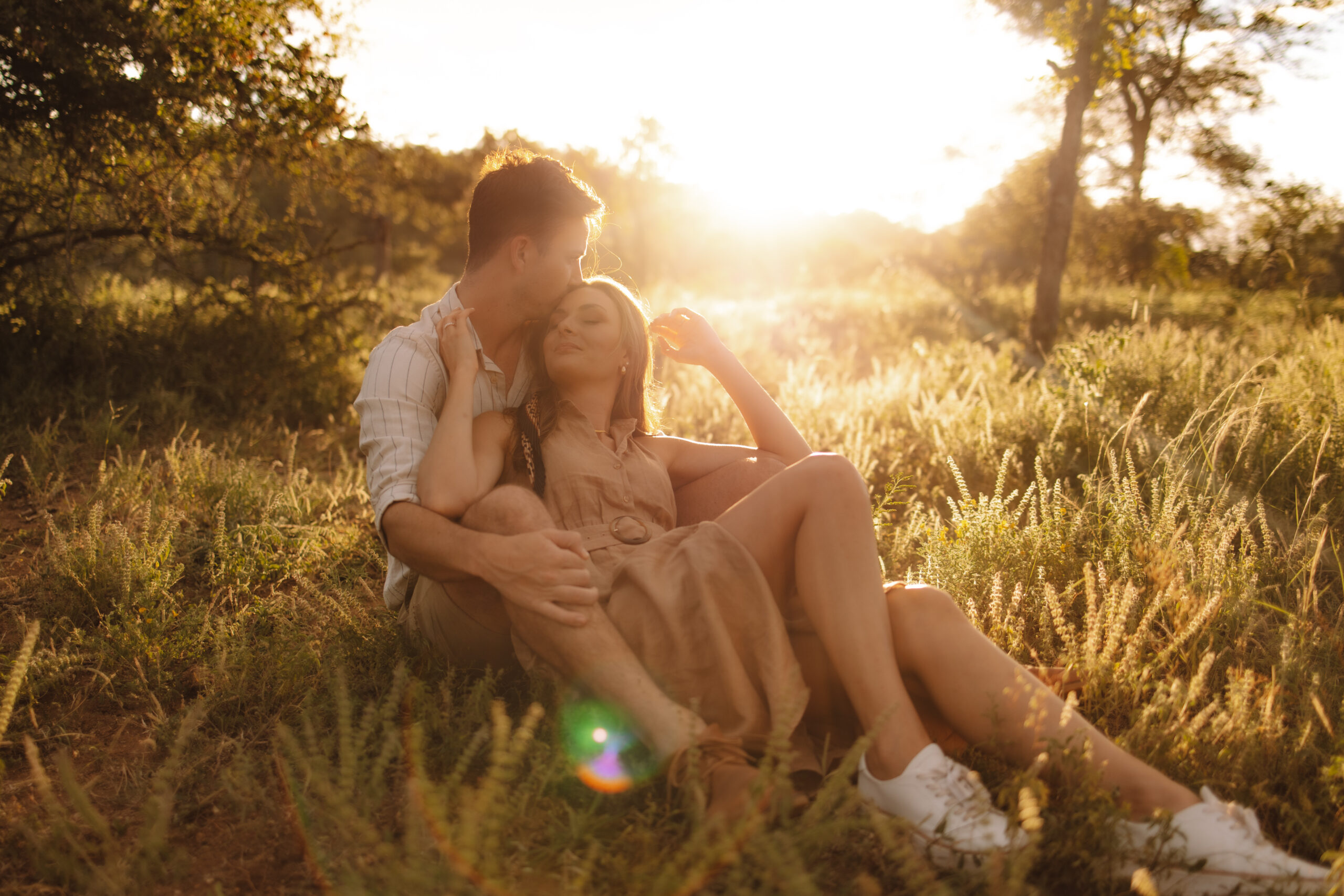 Couple sitting together in tall grass at golden hour during an intimate safari elopement