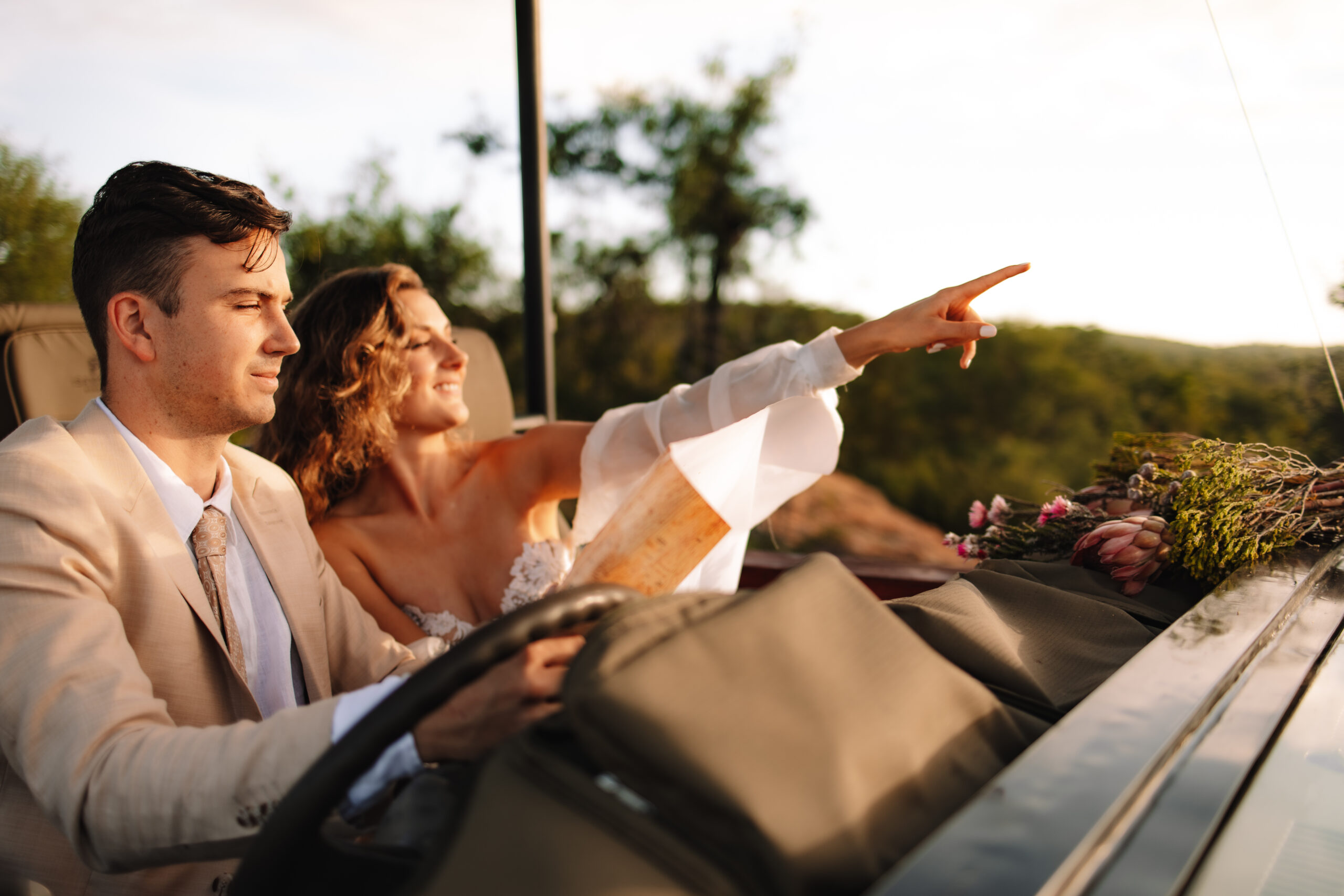 Bride and groom riding in an open safari vehicle at golden hour during a luxury South Africa safari elopement