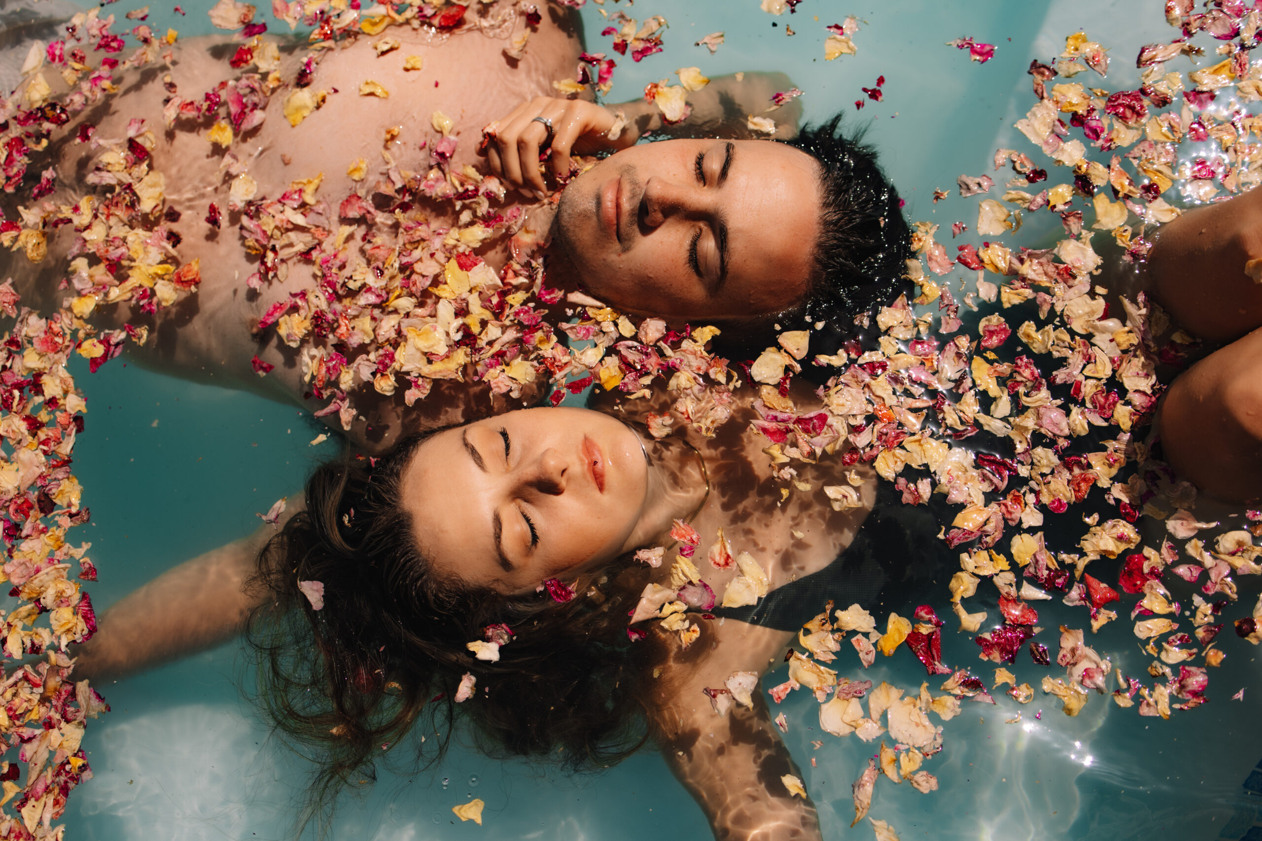 Newlyweds floating in water covered with flower petals after an intimate safari elopement