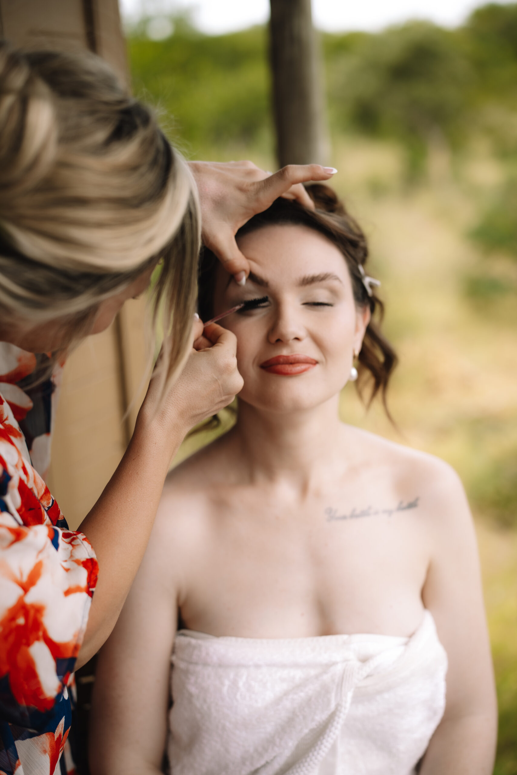 Bride having makeup applied on a lodge deck before her safari elopement in South Africa