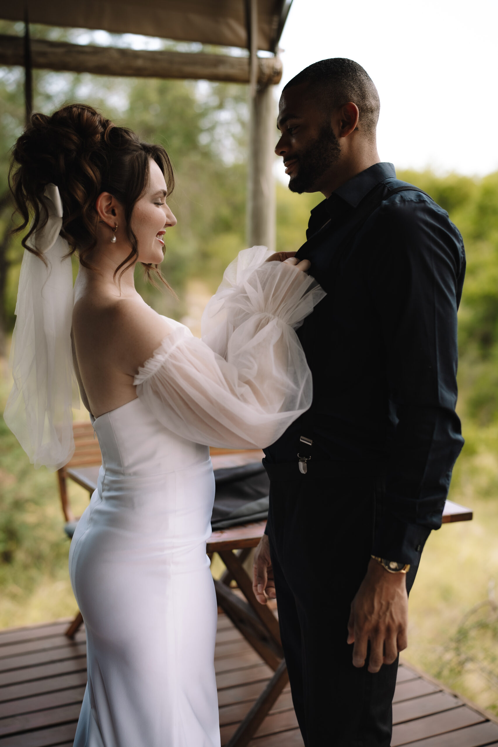 Bride adjusting the groom’s jacket during a quiet moment on a private lodge deck