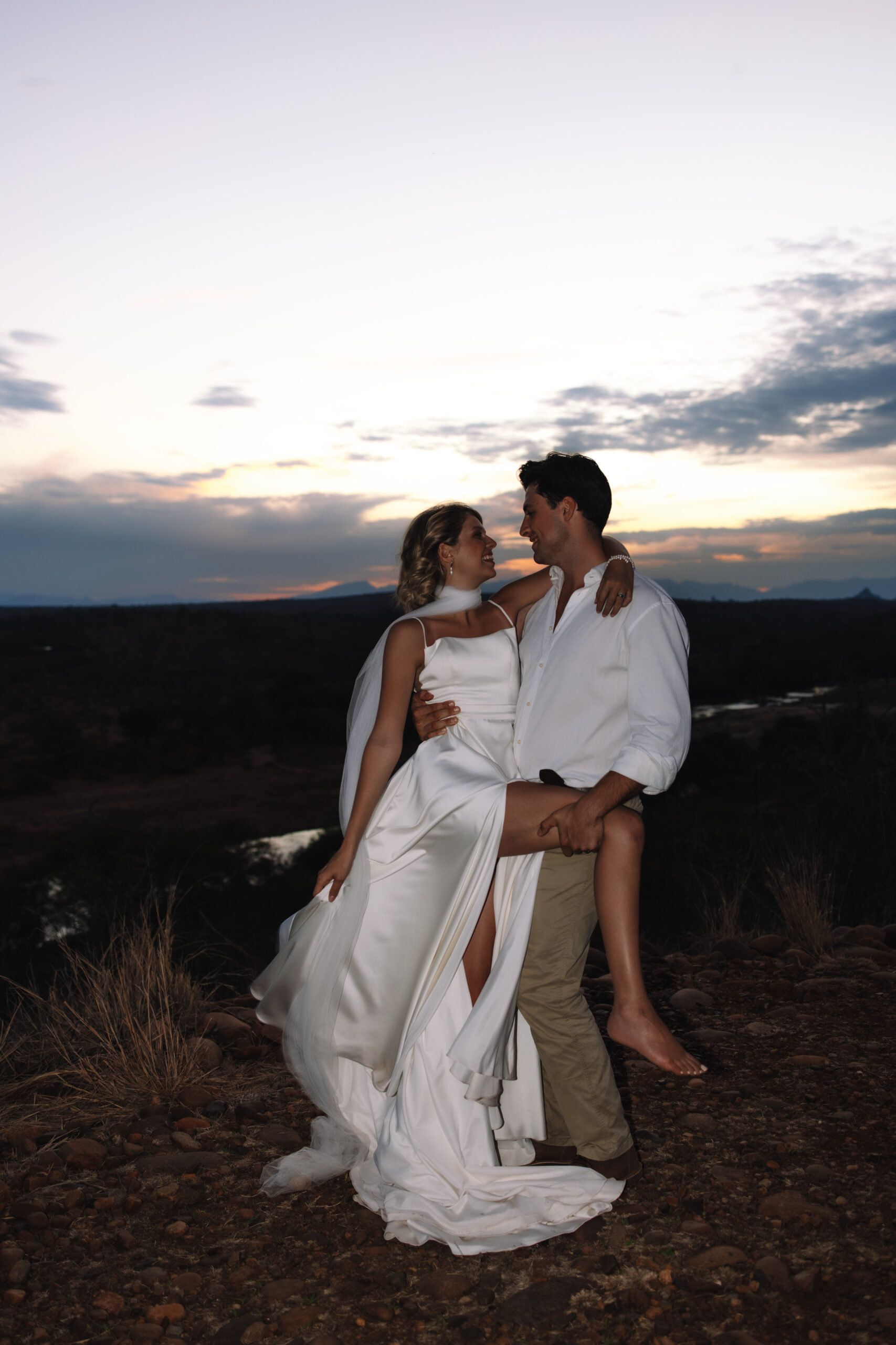 Couple embracing on a rocky overlook at dusk after exchanging vows during a safari elopement in South Africa