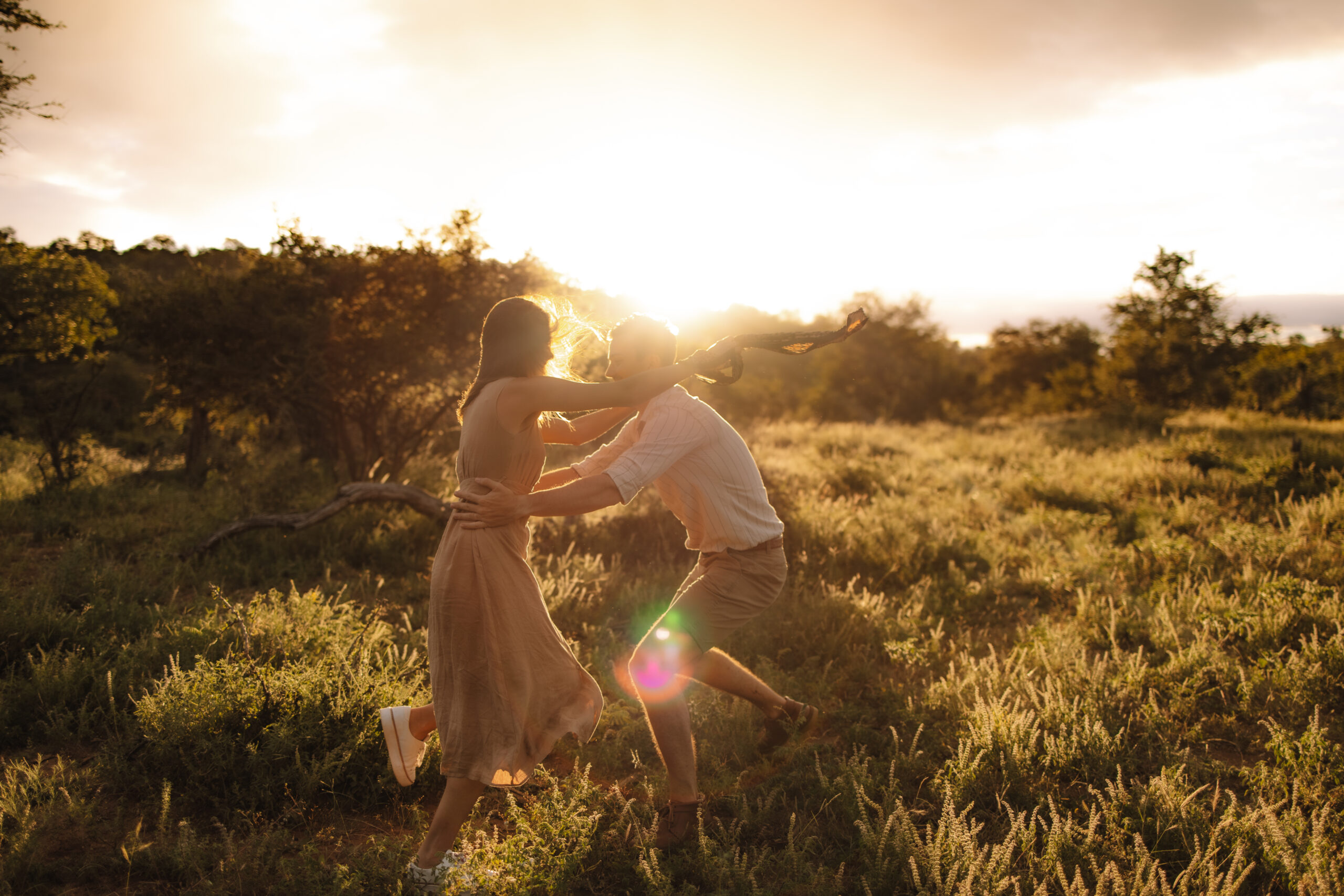 Couple running together through tall grass at golden hour during an intimate safari celebration