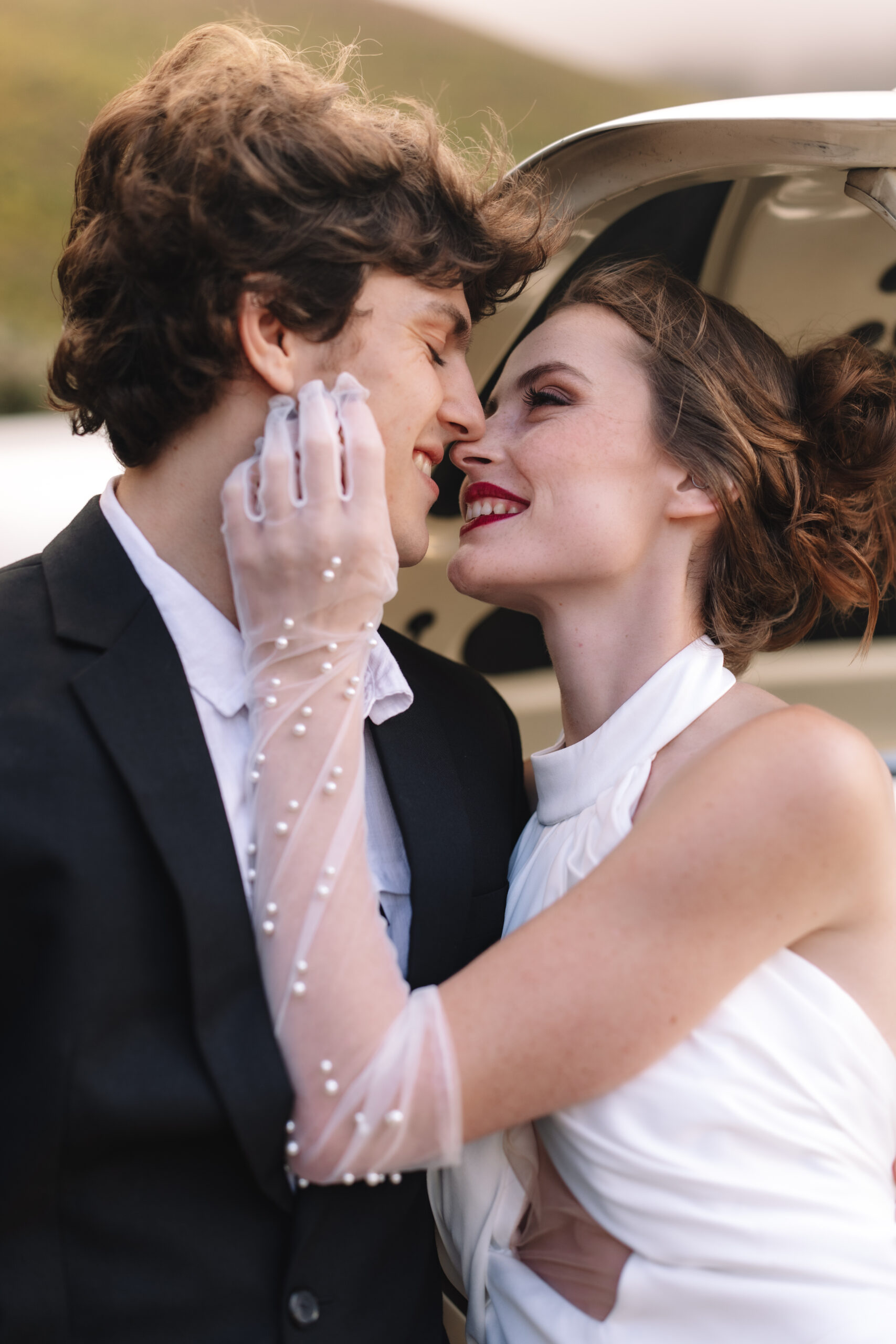 Close-up Cape Town elopement portrait of a bride and groom embracing beside a vintage car, capturing soft emotion and connection.