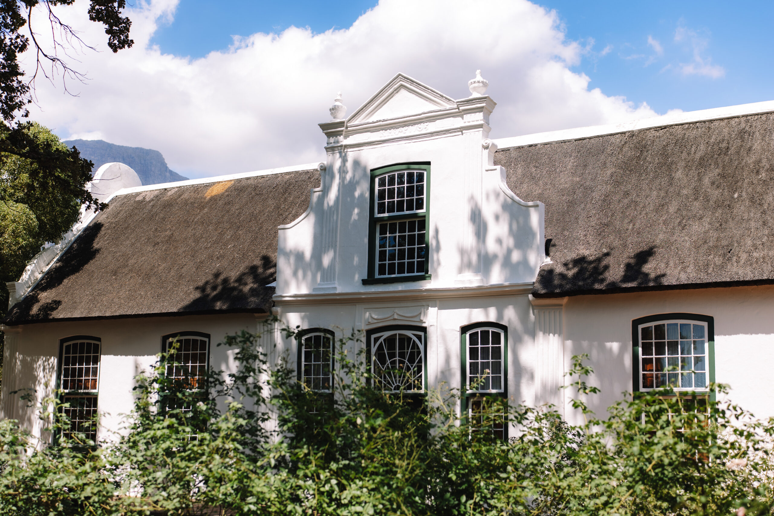 Historic white Cape Dutch estate exterior surrounded by greenery in the Western Cape.