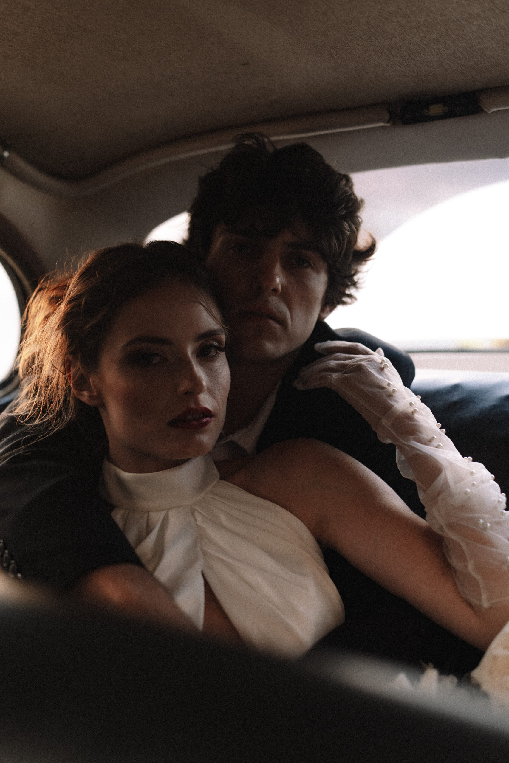 Moody portrait of bride and groom inside vintage car during intimate elopement.