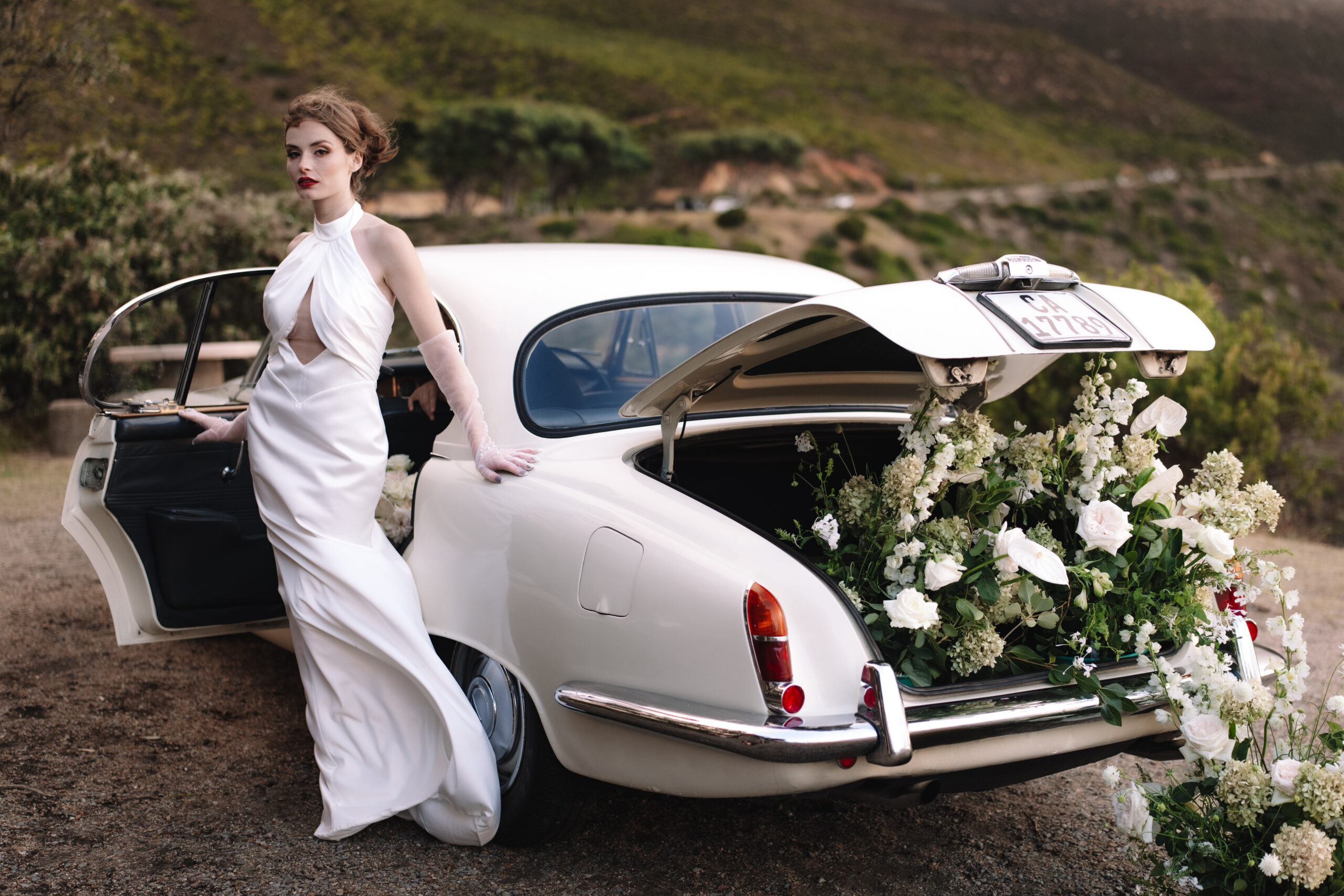 Bride stepping out of vintage car with overflowing florals at cape town wedding locations.