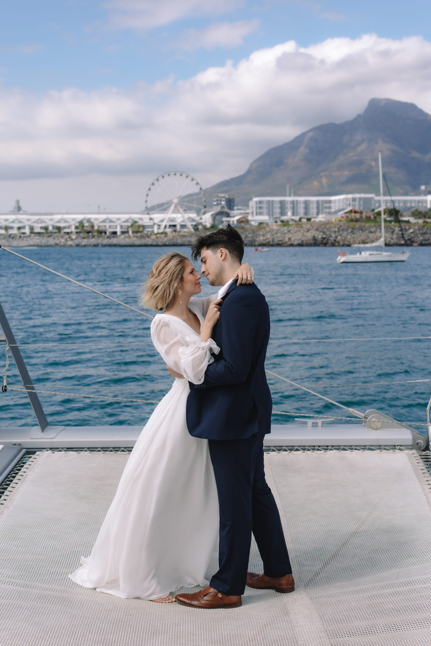 Couple embracing on a yacht with Table Mountain behind them, showcasing unique cape town wedding locations.
