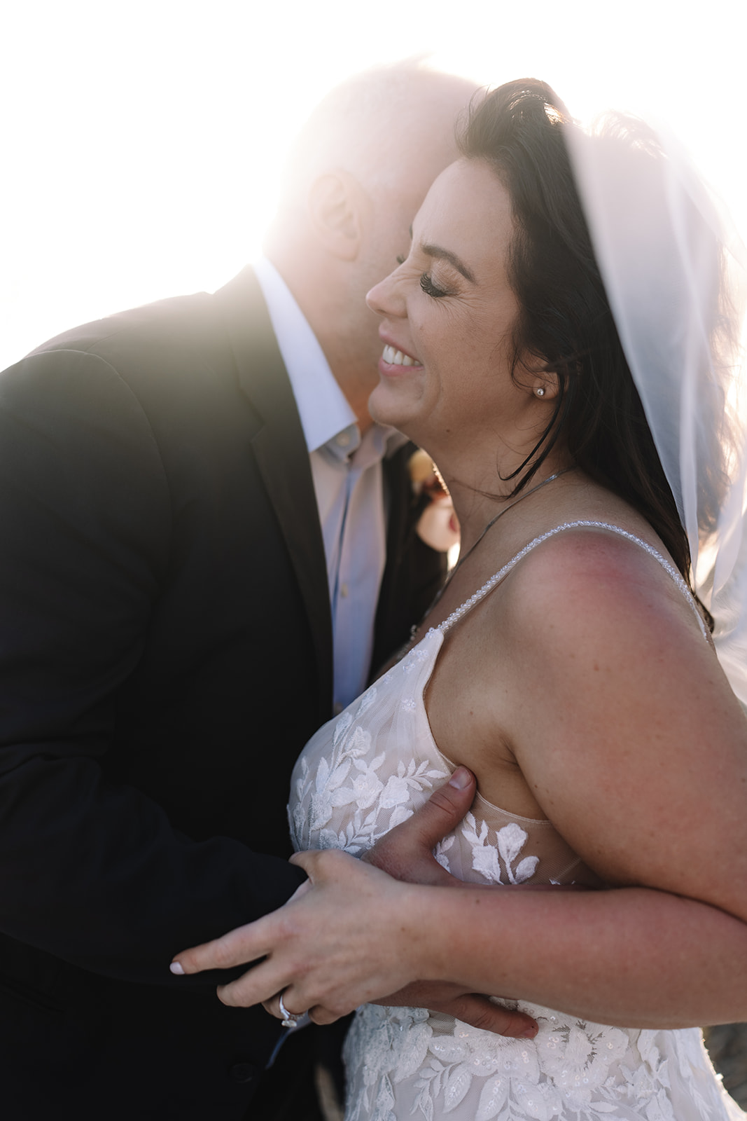 Close up of groom hugging bride tight as she smiles with joy after Stony Point Nature Reserve wedding.
