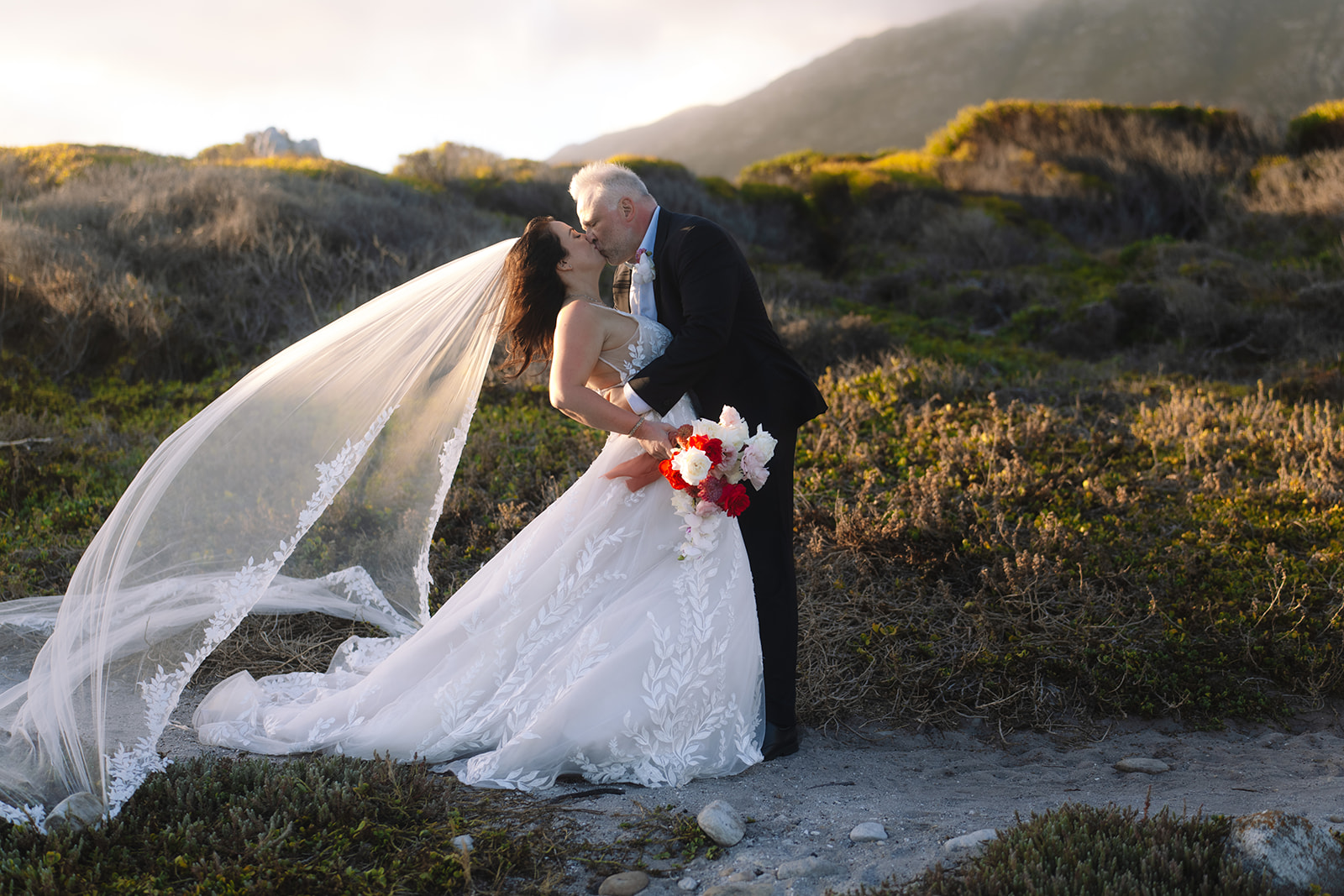 Bride and groom embracing along the rocky coastline in Betty’s Bay