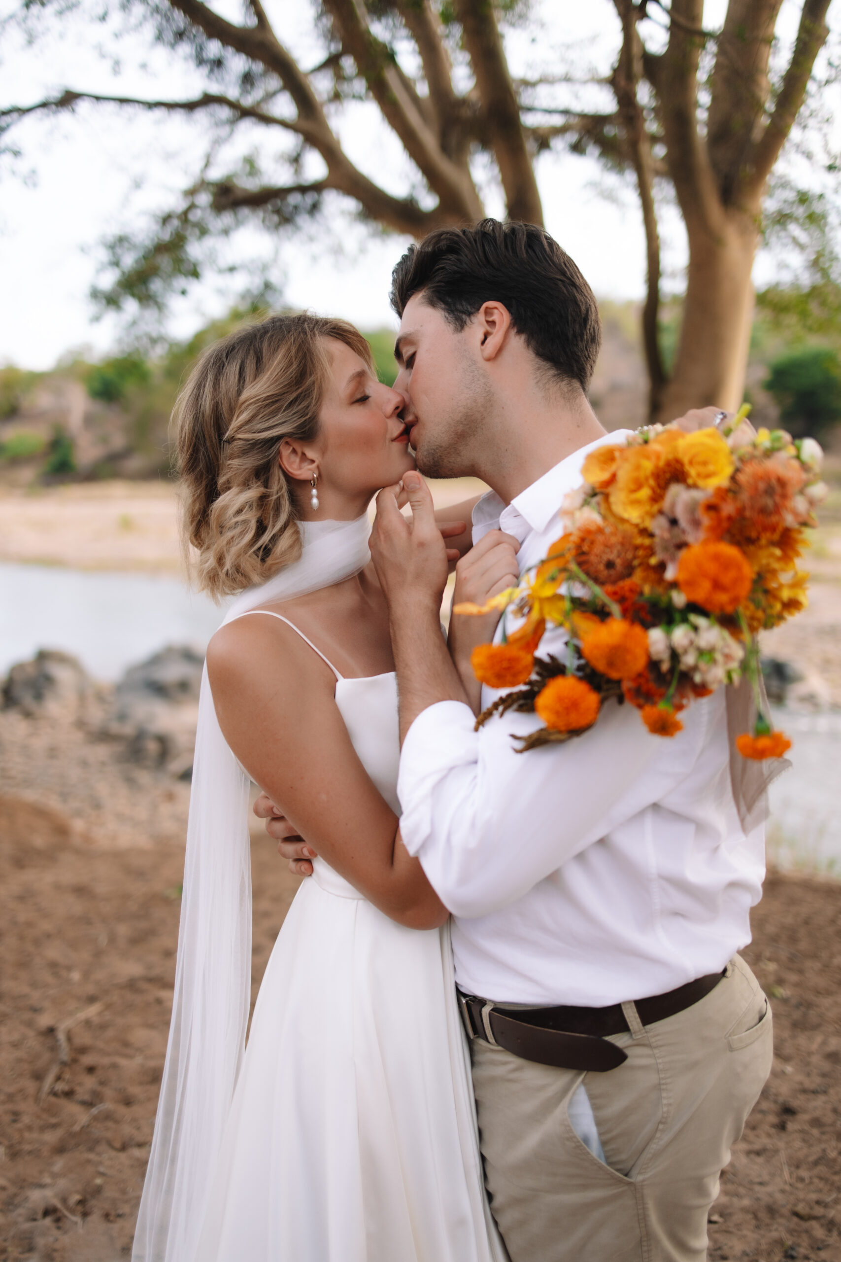 Intimate kiss beside a river during a luxury safari elopement in South Africa.
