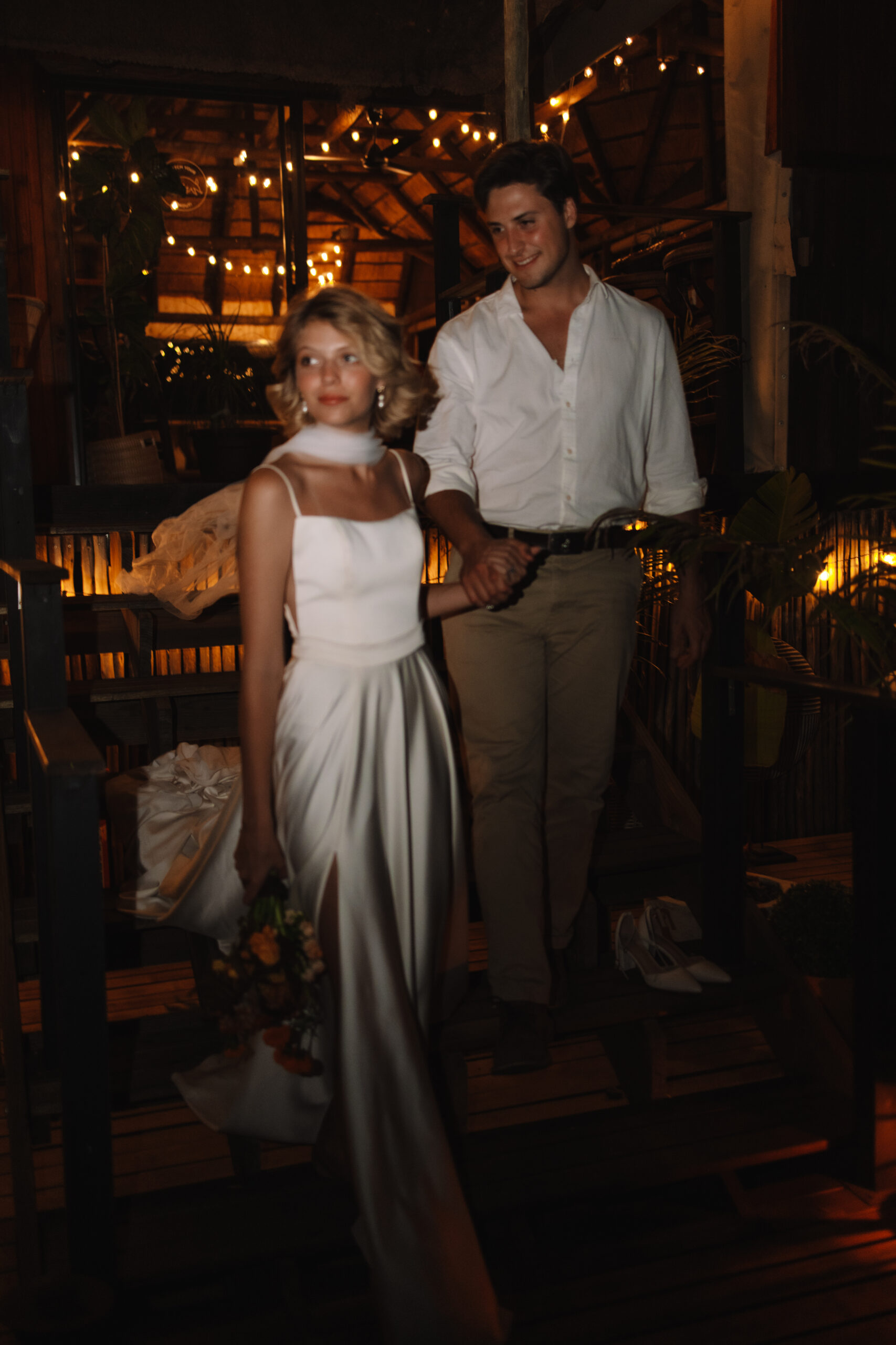 Bride and groom walking through a candlelit safari lodge during their Cape Town honeymoon.