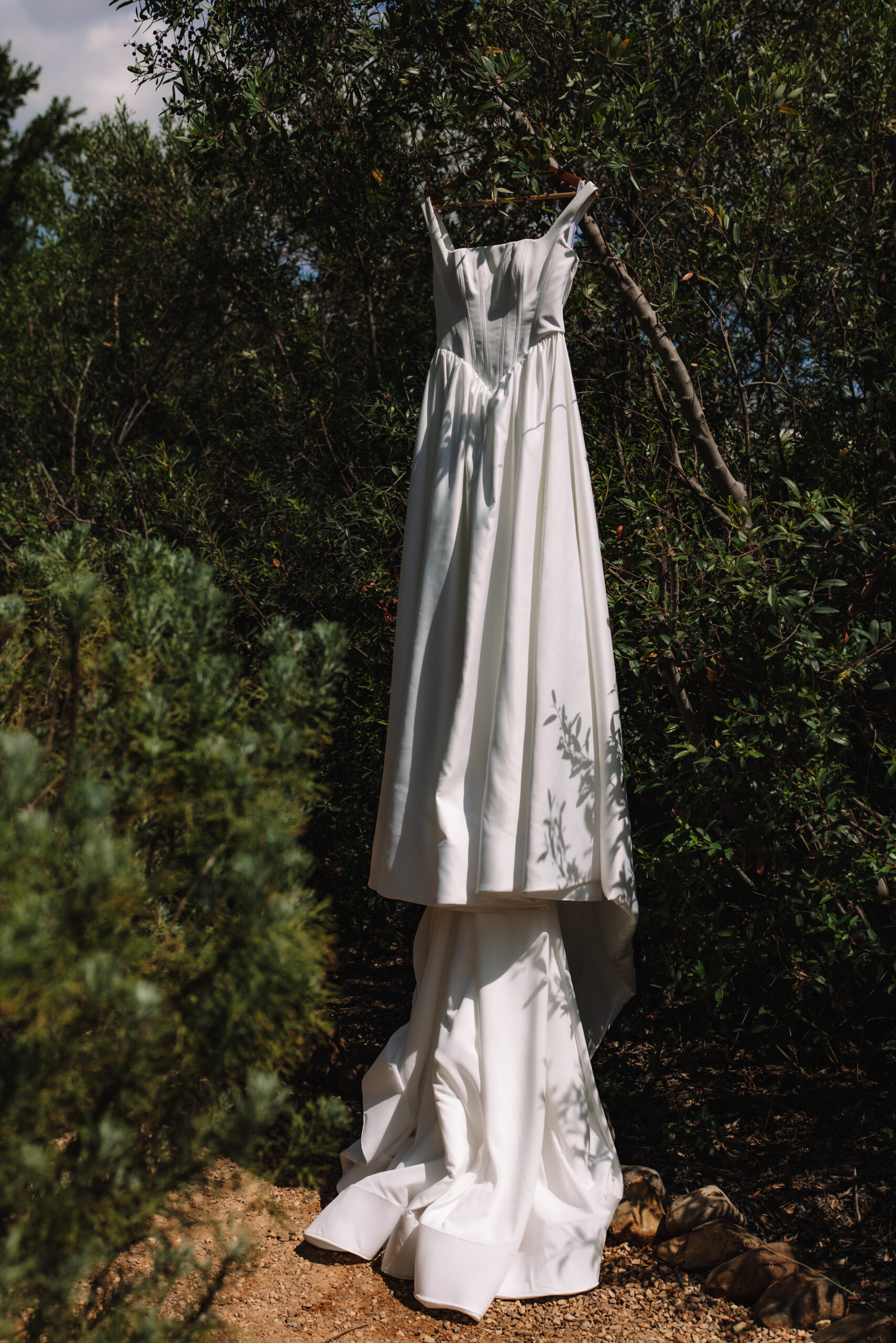 Minimalist wedding dress hanging in natural greenery before a safari elopement in South Africa.