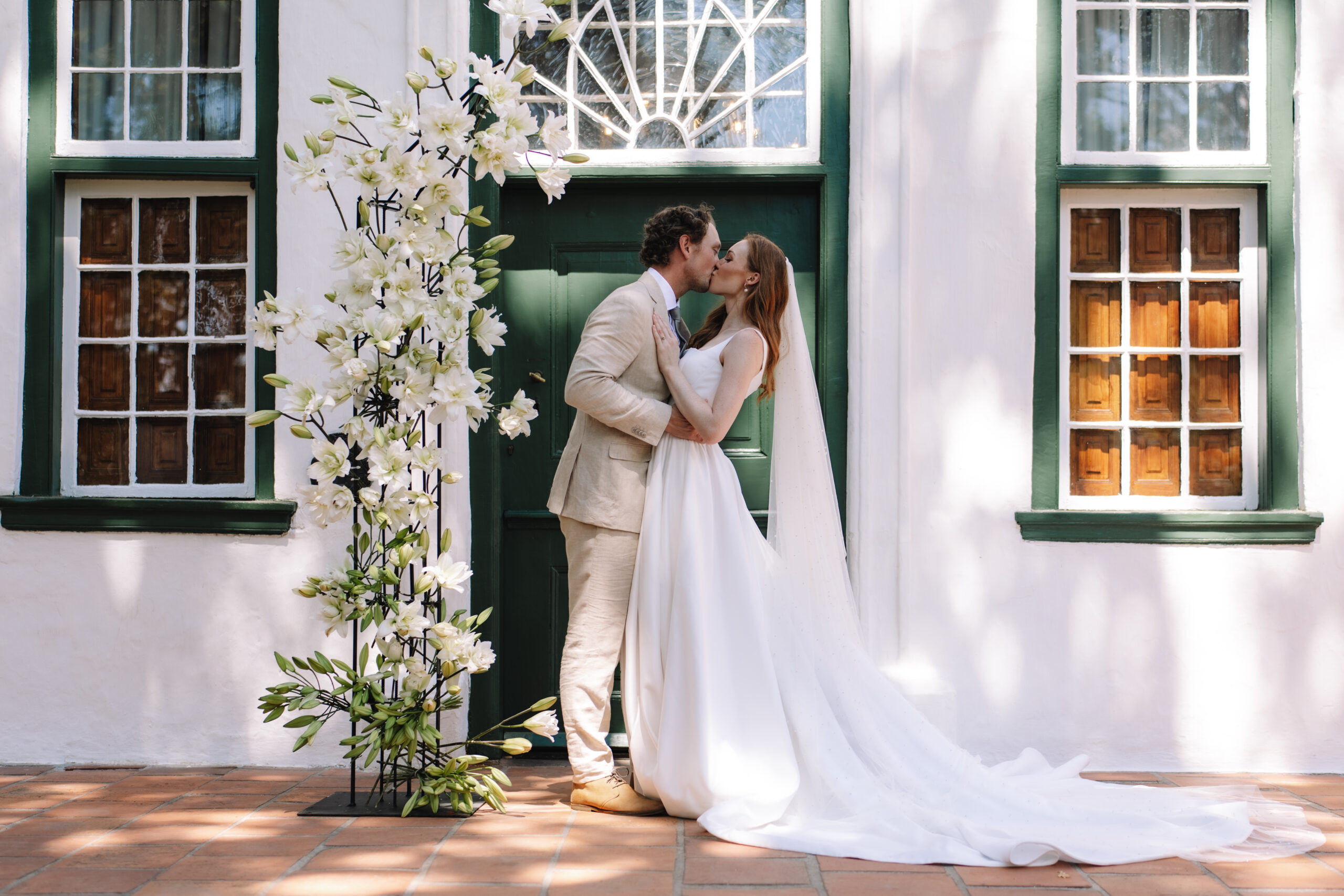 Newlyweds kissing at a Cape Dutch estate during their Cape Town honeymoon.