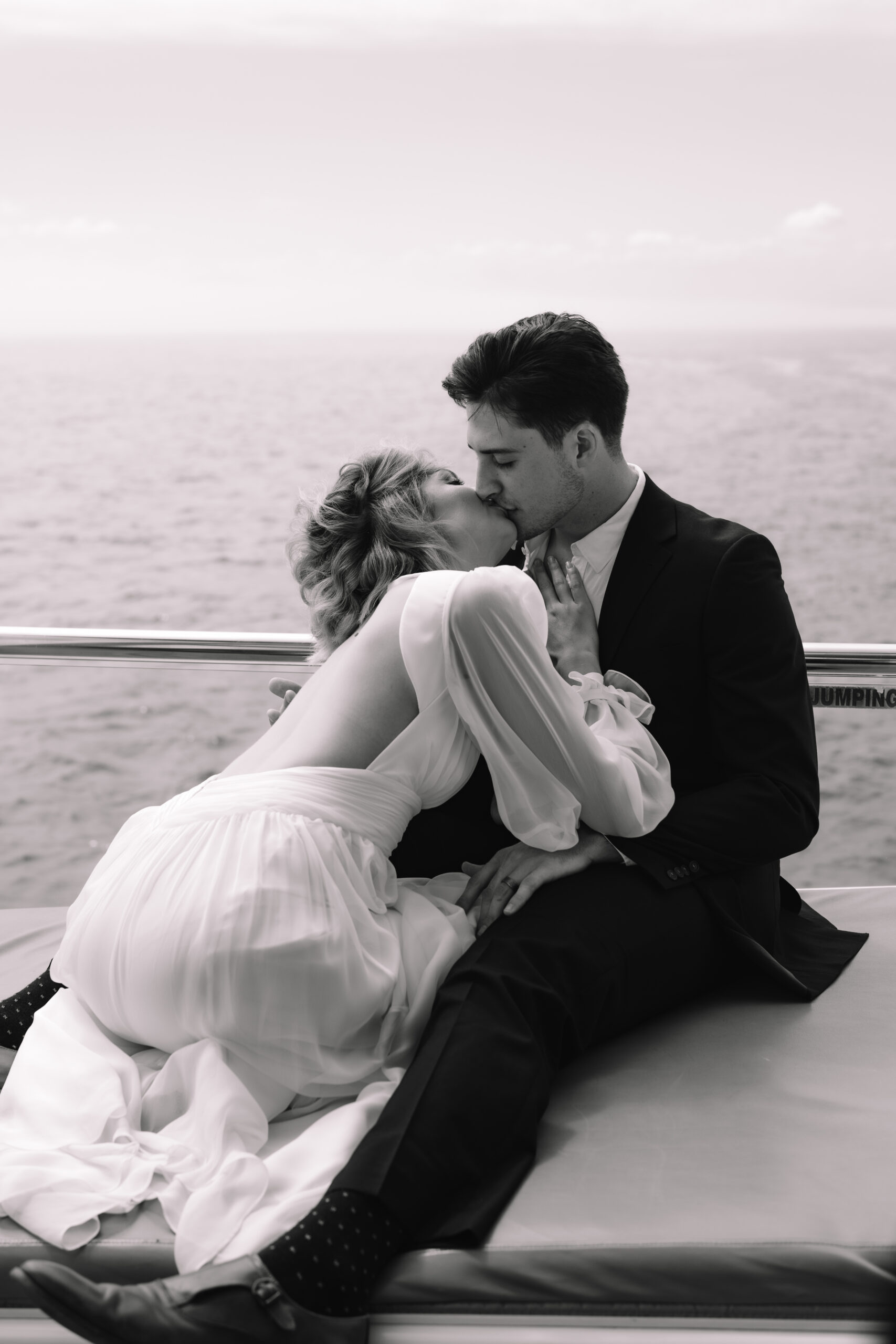 Newlyweds kissing on a yacht during their Cape Town honeymoon along the Atlantic coastline.