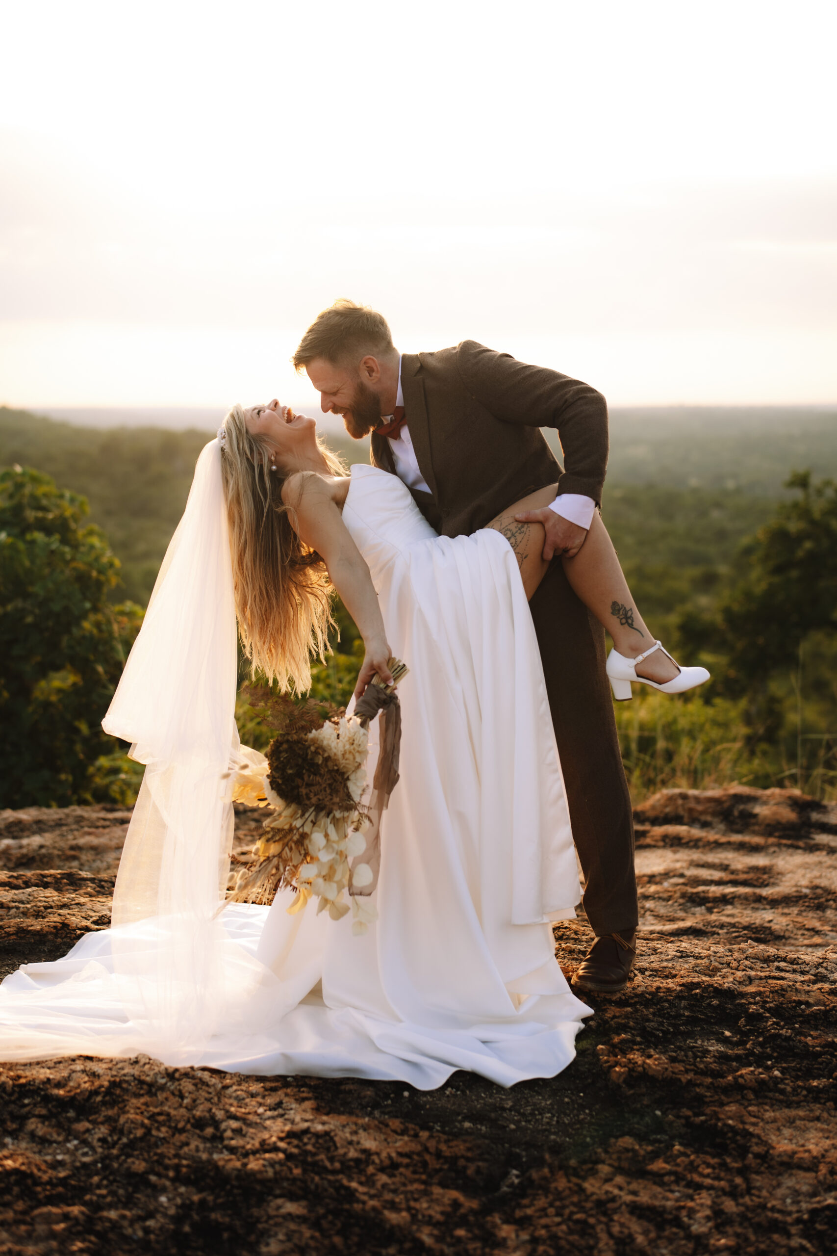 Bride and groom dancing and laughing on a cliffside at sunset during an intimate South Africa elopement