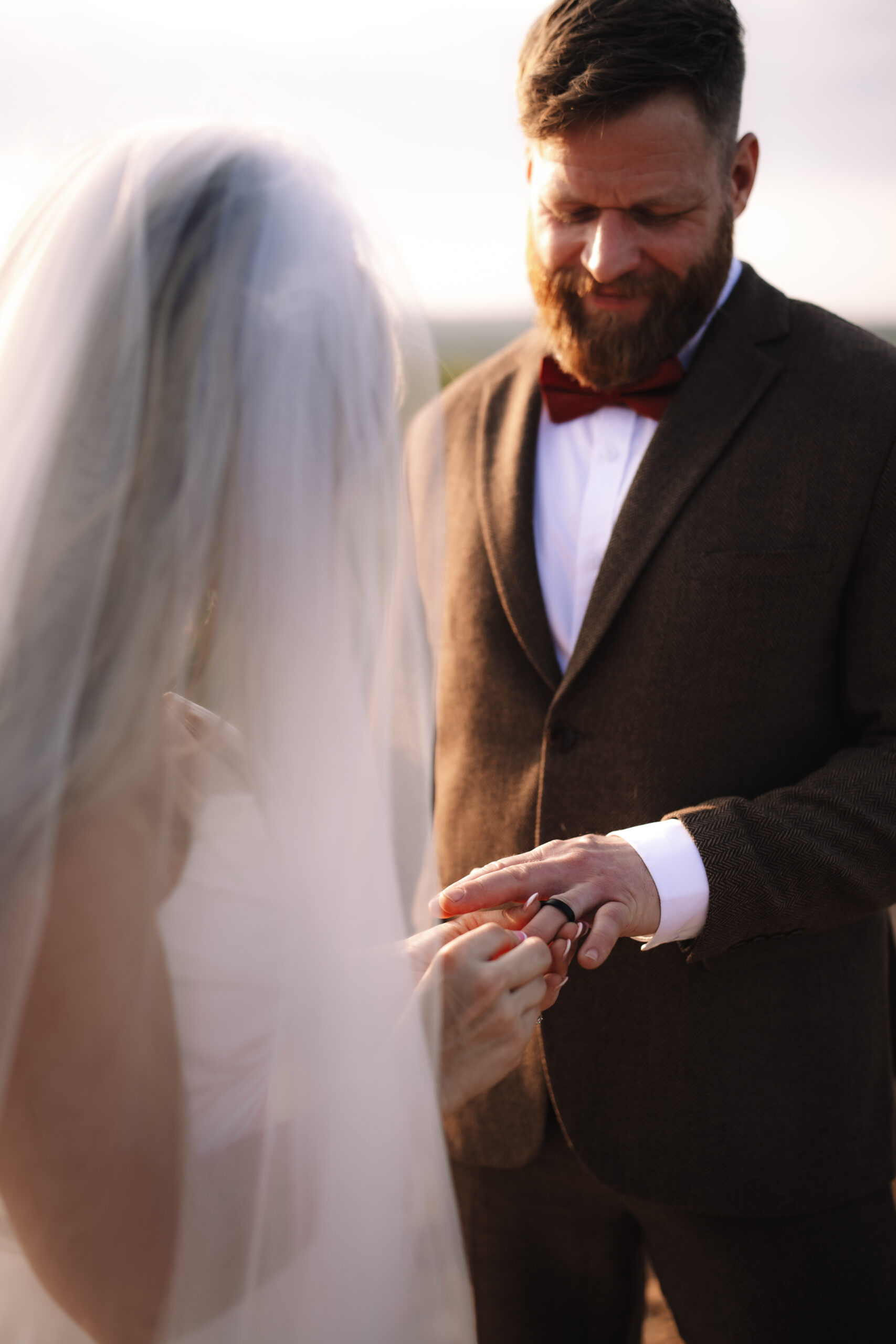 Groom smiling as bride places a wedding ring on his finger during an intimate safari elopement in Africa