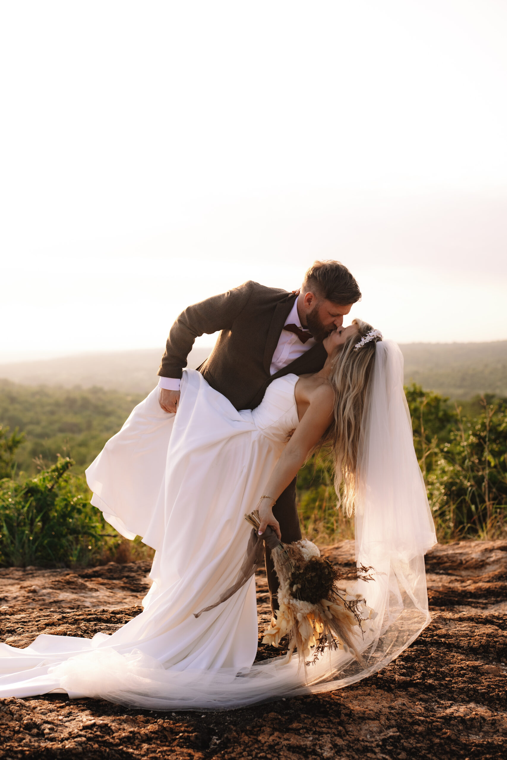 Groom dipping bride for a kiss at sunset on a cliffside during a safari elopement in Africa