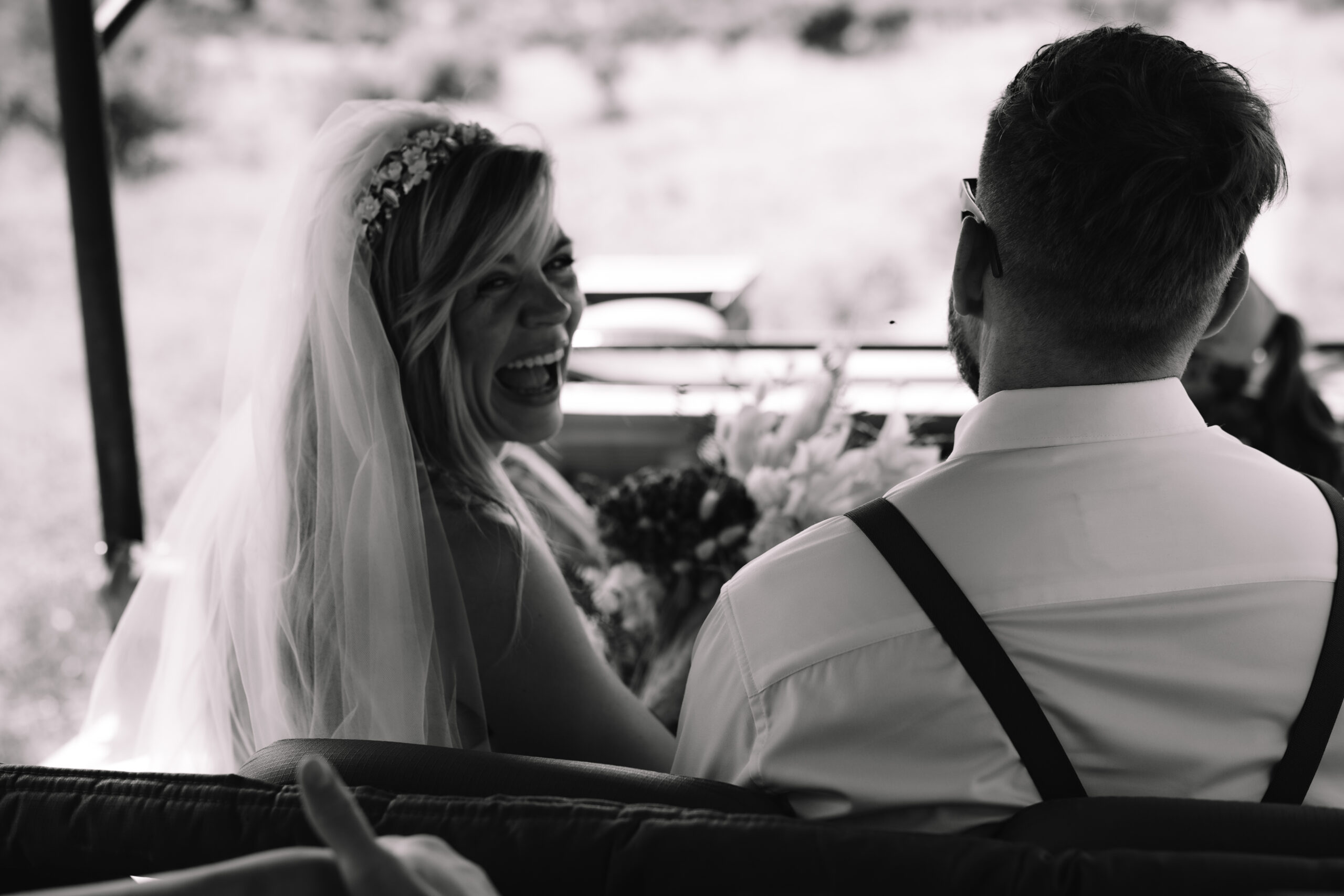 Black and white photo of bride laughing with groom while riding in a safari vehicle on their elopement day