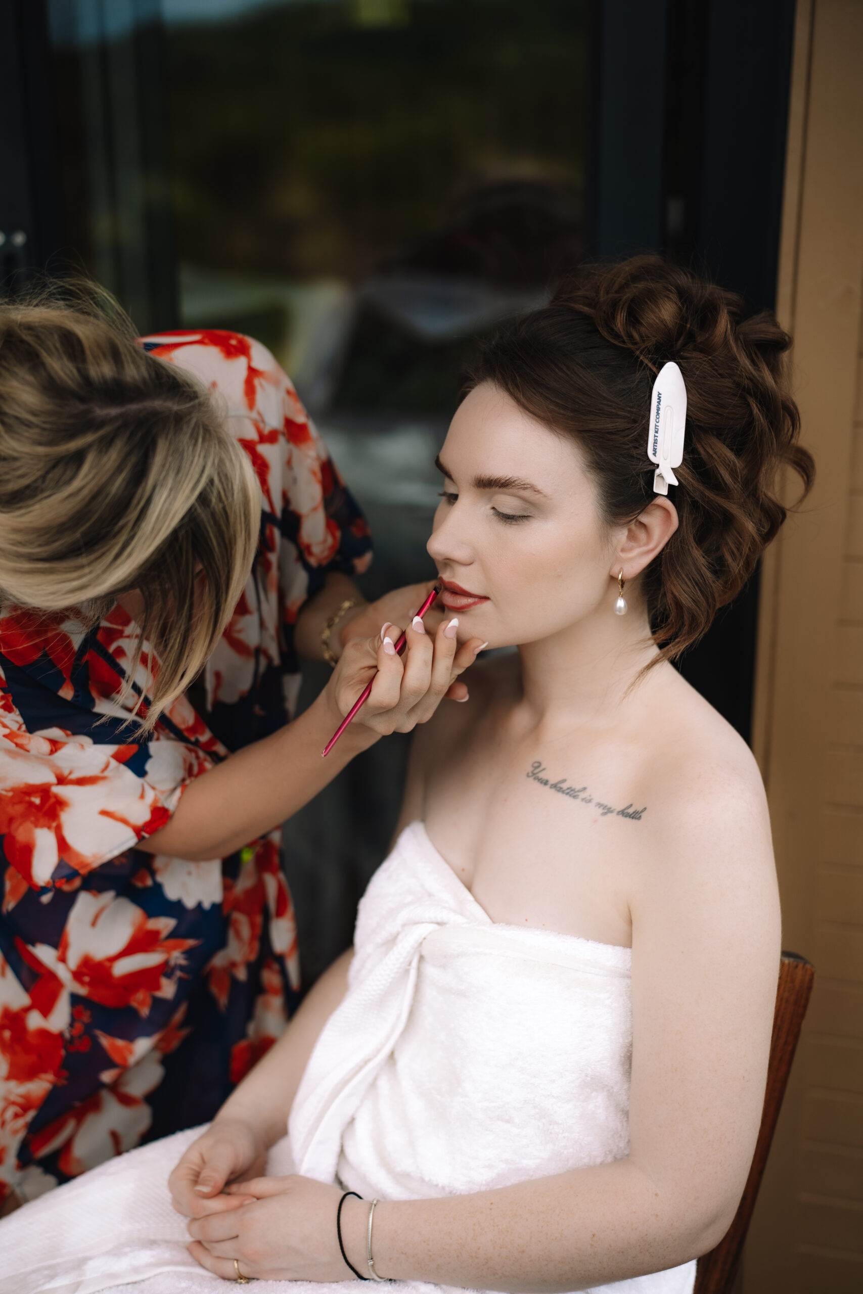 Bride having lipstick applied during wedding morning preparations at a safari lodge